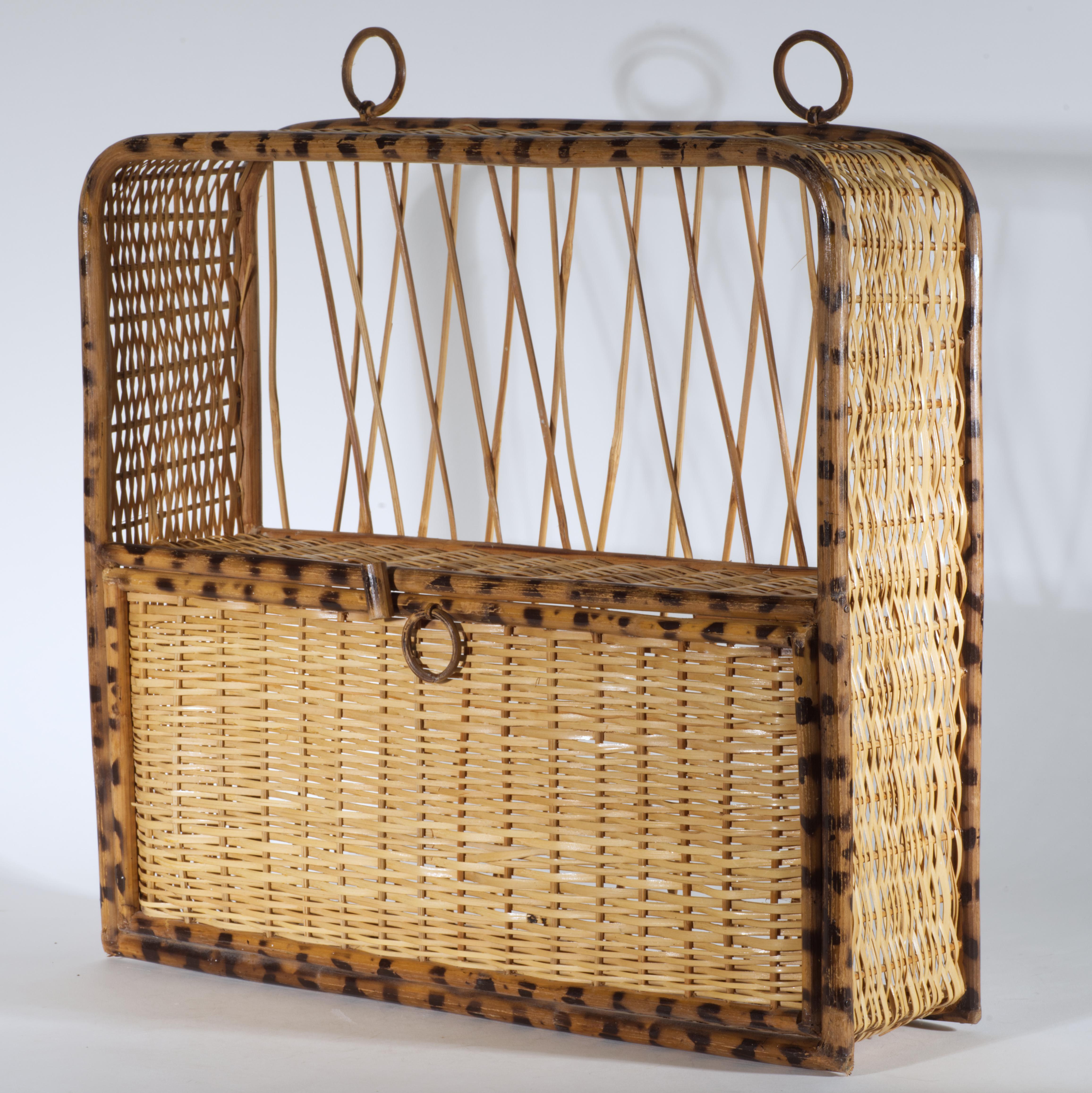 Cette étagère vintage en bambou et rotin, de couleur brûlée ou écaille, présente une structure à deux niveaux avec une porte tombante sur l'étagère du bas. L'étagère est munie de deux anneaux en bambou fixés sur le dessus pour la fixer au mur ; un