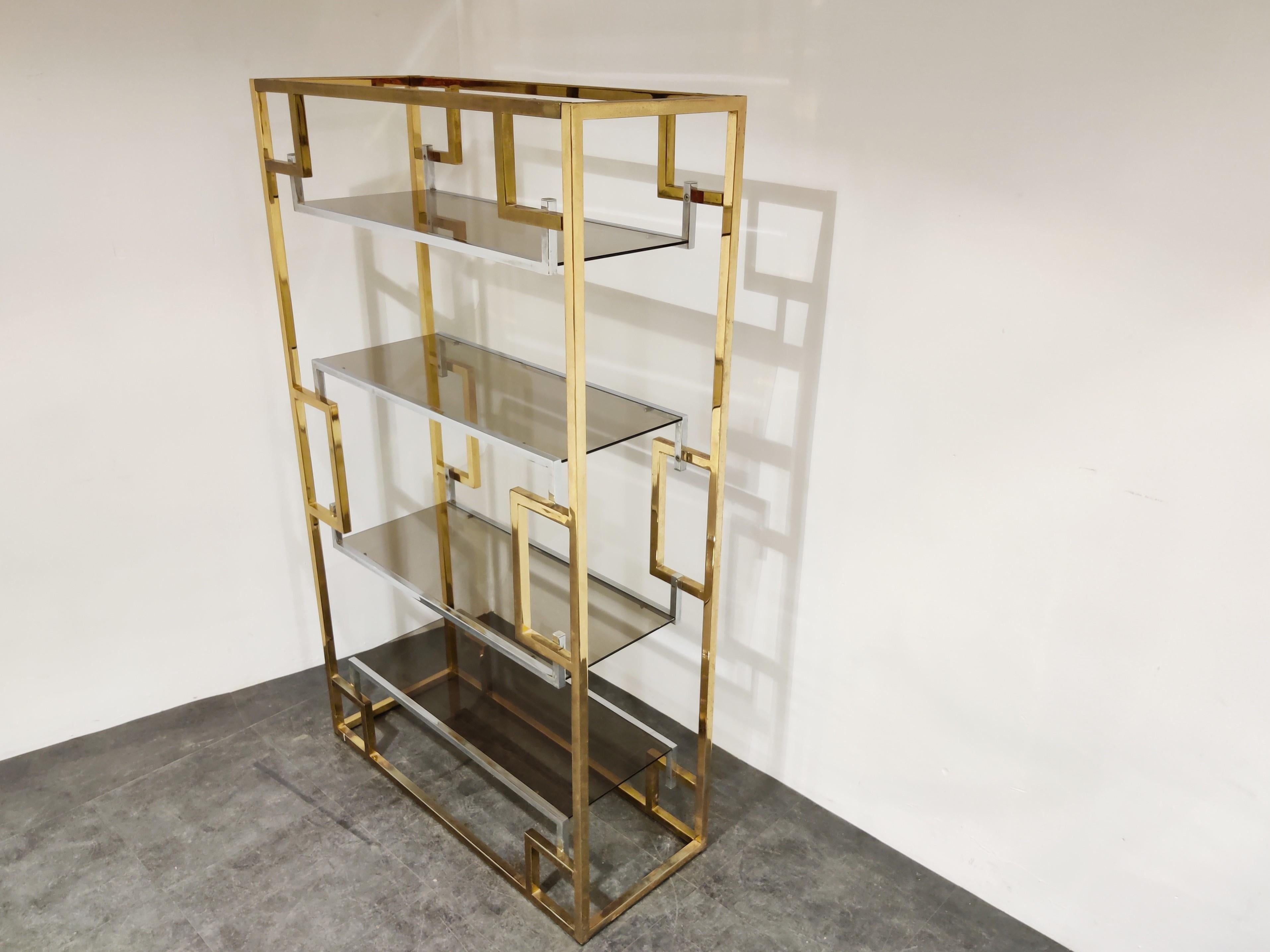 Hollywood regency wall unit designed by Willy Rizzo.

It consists of symmetrical brass and chrome shelves with smoked glass tops.

Original condition, some wear on the brass and chrome, original glass.

1970s, Italy

Measures: Height 180 cm/