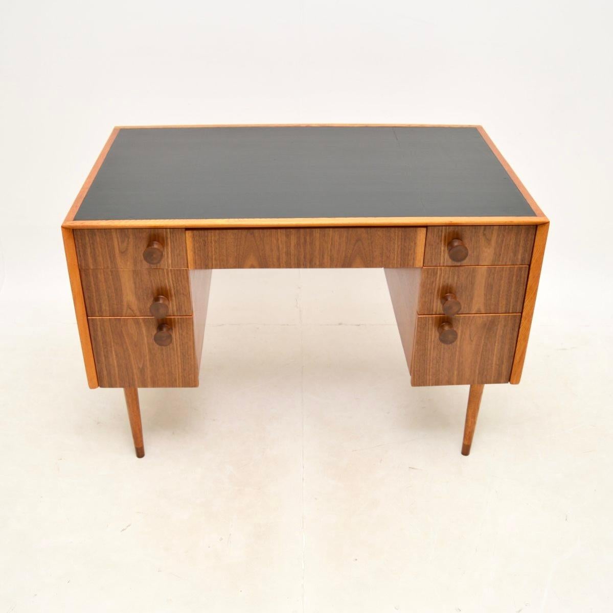 A very stylish and well made vintage walnut and oak leather top desk. This was made in England, it dates from around the 1950-60’s.

It is beautifully designed and is of superb quality, the oak carcass has exposed dovetailed joints at the top edges,