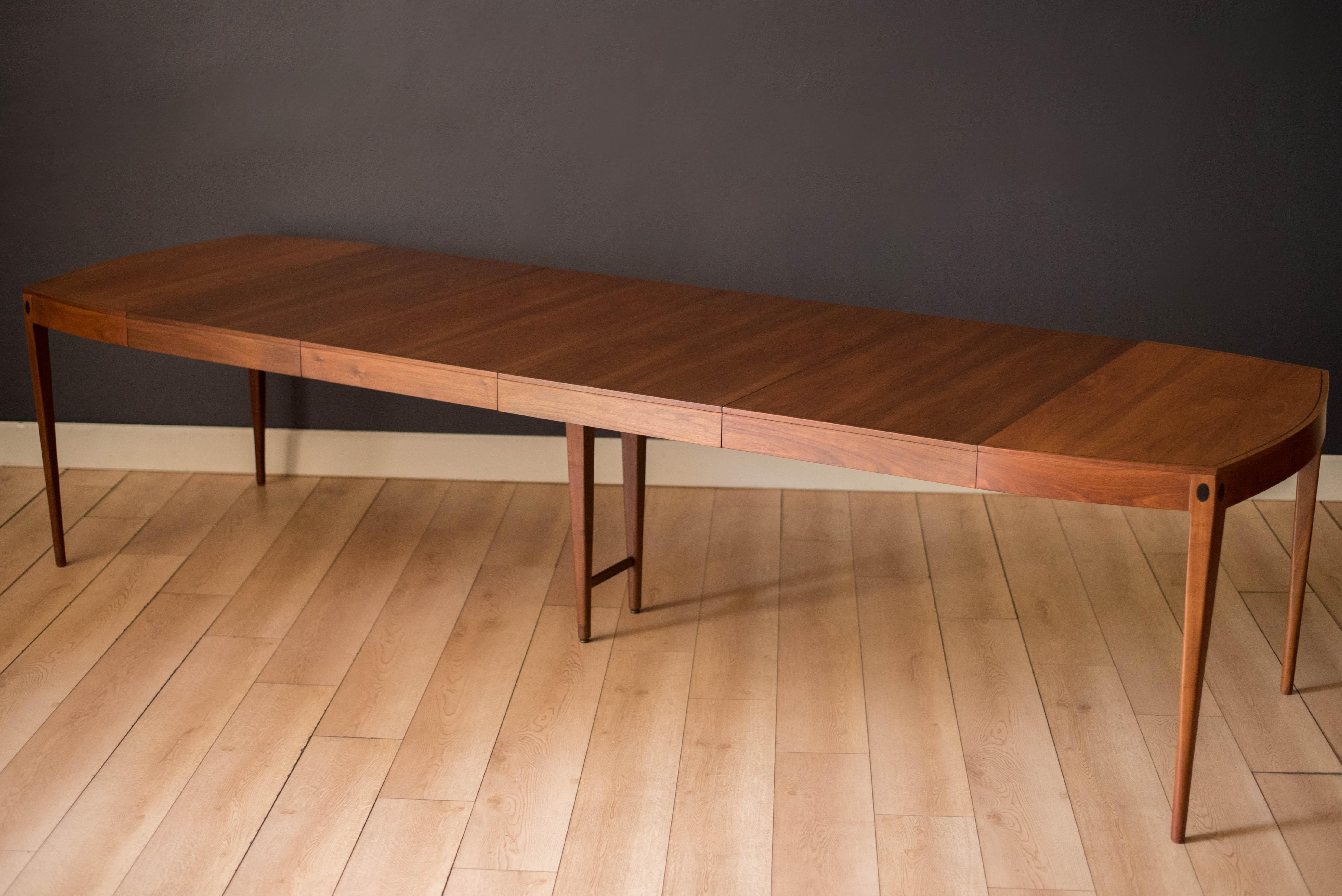 Mid Century Modern Directional dining table designed by Kipp Stewart for Calvin Furniture in walnut, circa 1960's. Features rosewood inlay and a unique shaped top that expands with four separate leaves. Comfortably seats up to 10-12 guests and