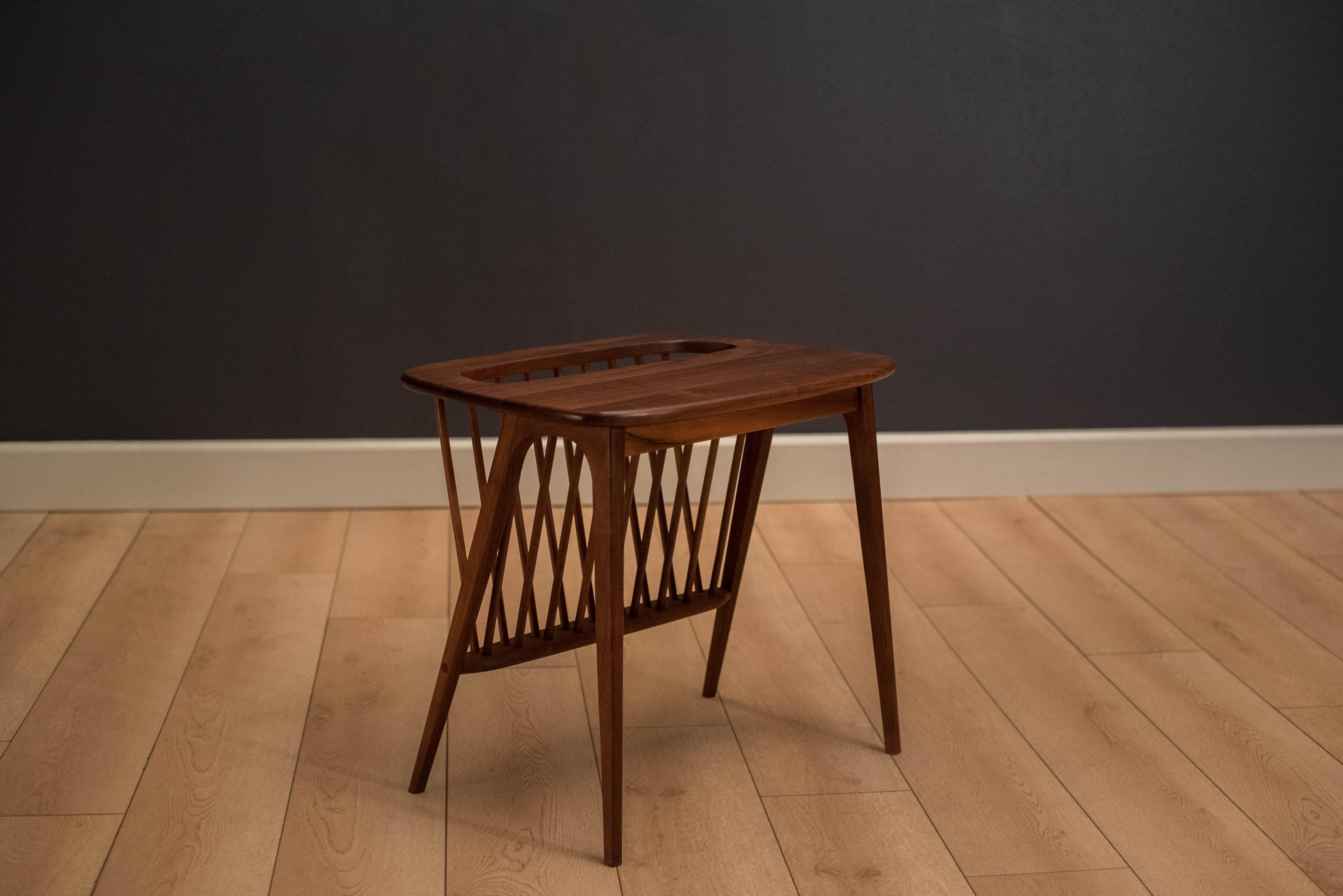 Mid century side table designed by Arthur Umanoff. This versatile piece is made of solid planked walnut and includes an attached magazine rack.