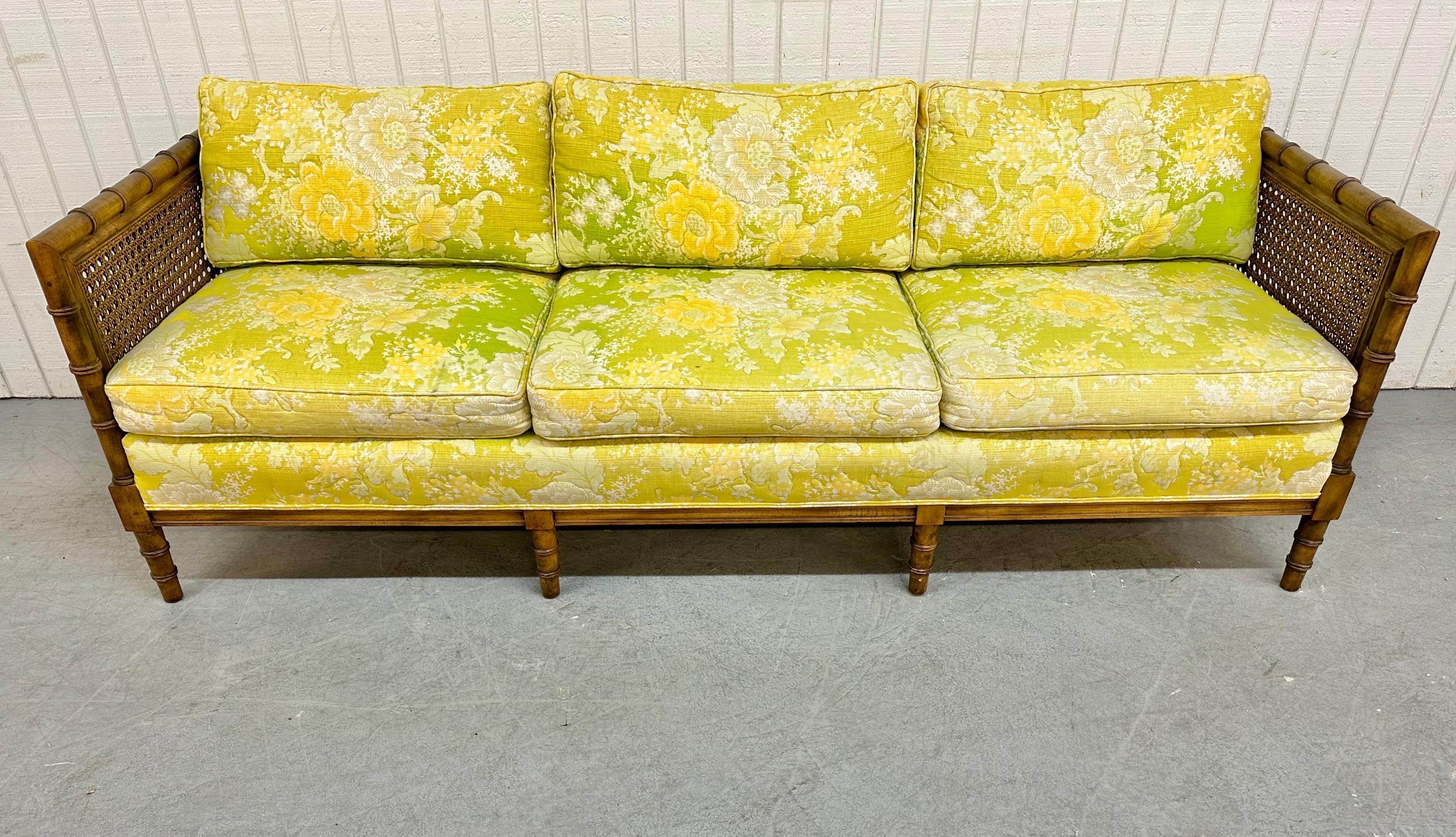 This listing is for a vintage Bamboo Floral Cane Sofa. Featuring a beautiful bright greenish yellow floral upholstery, bamboo style frame, canned arm rests, and a walnut colored frame.