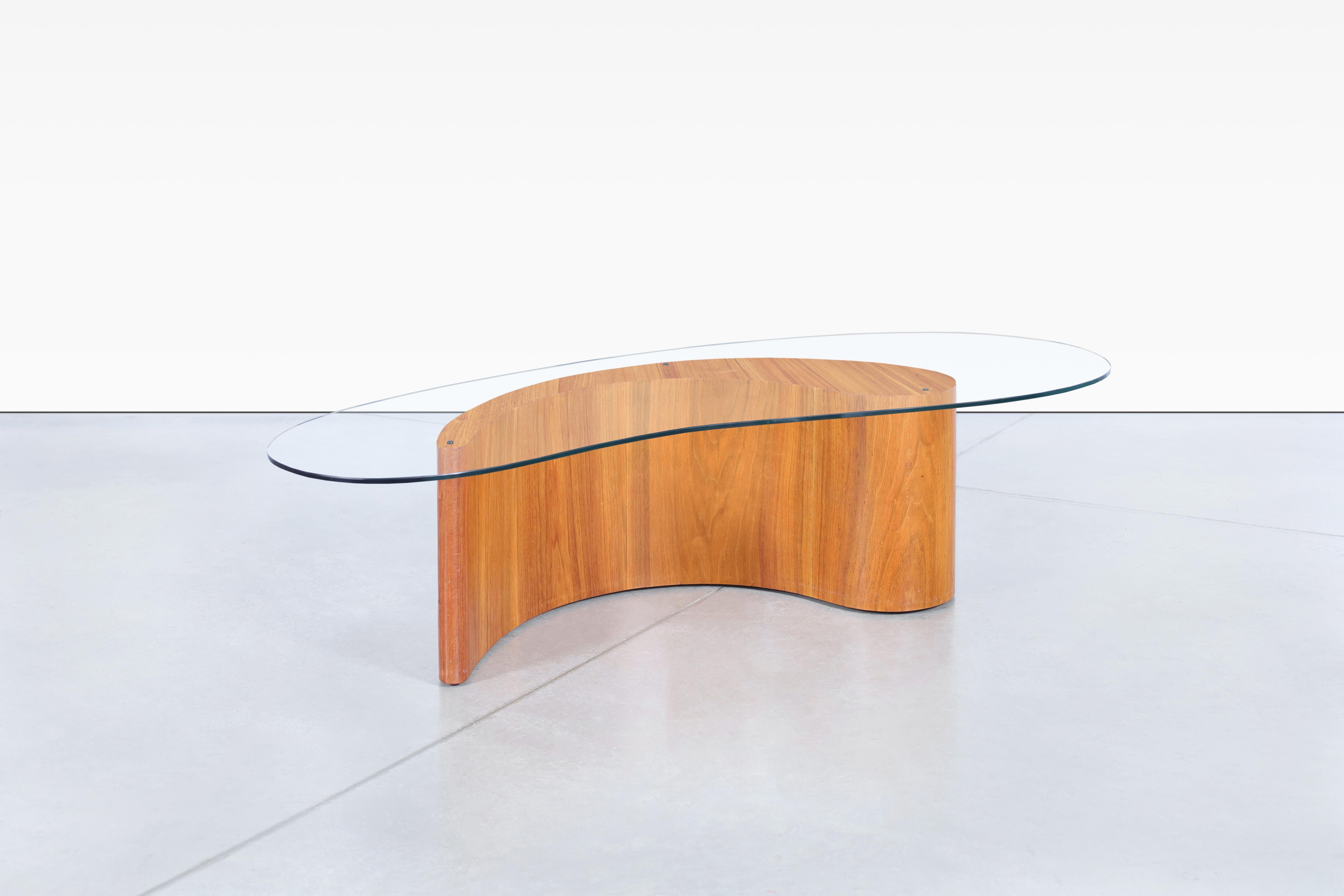 Fabriquée aux États-Unis dans les années 1960, cette table basse présente une remarquable combinaison de noyer et de verre. La magnifique base en noyer respire la sophistication, tandis que le plateau en verre unique laisse passer la lumière,