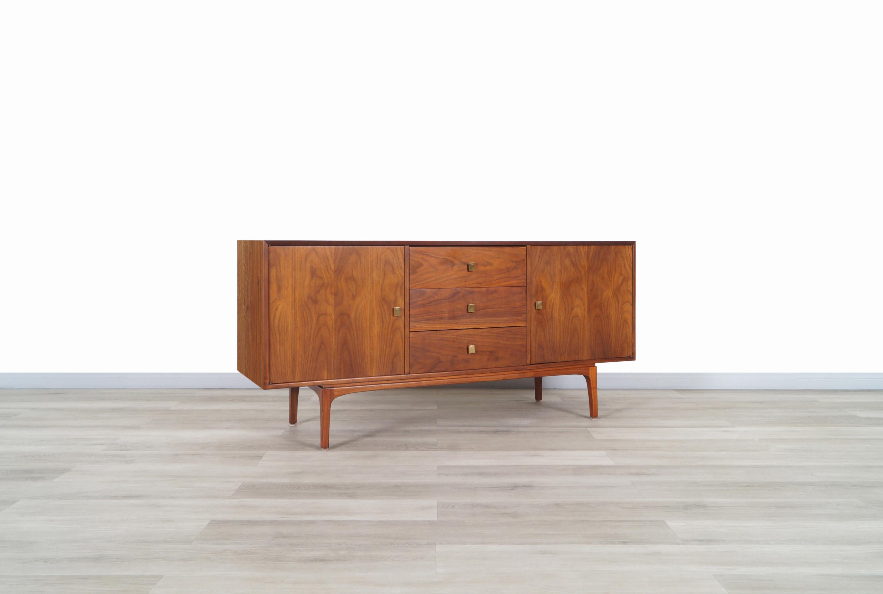 Beautiful vintage walnut credenza designed by John Keal for Brown Saltman in United States, circa 1960s. Features two doors on each side, that when opened we can see adjustable shelves that have a large storage space, and in the center, it has three