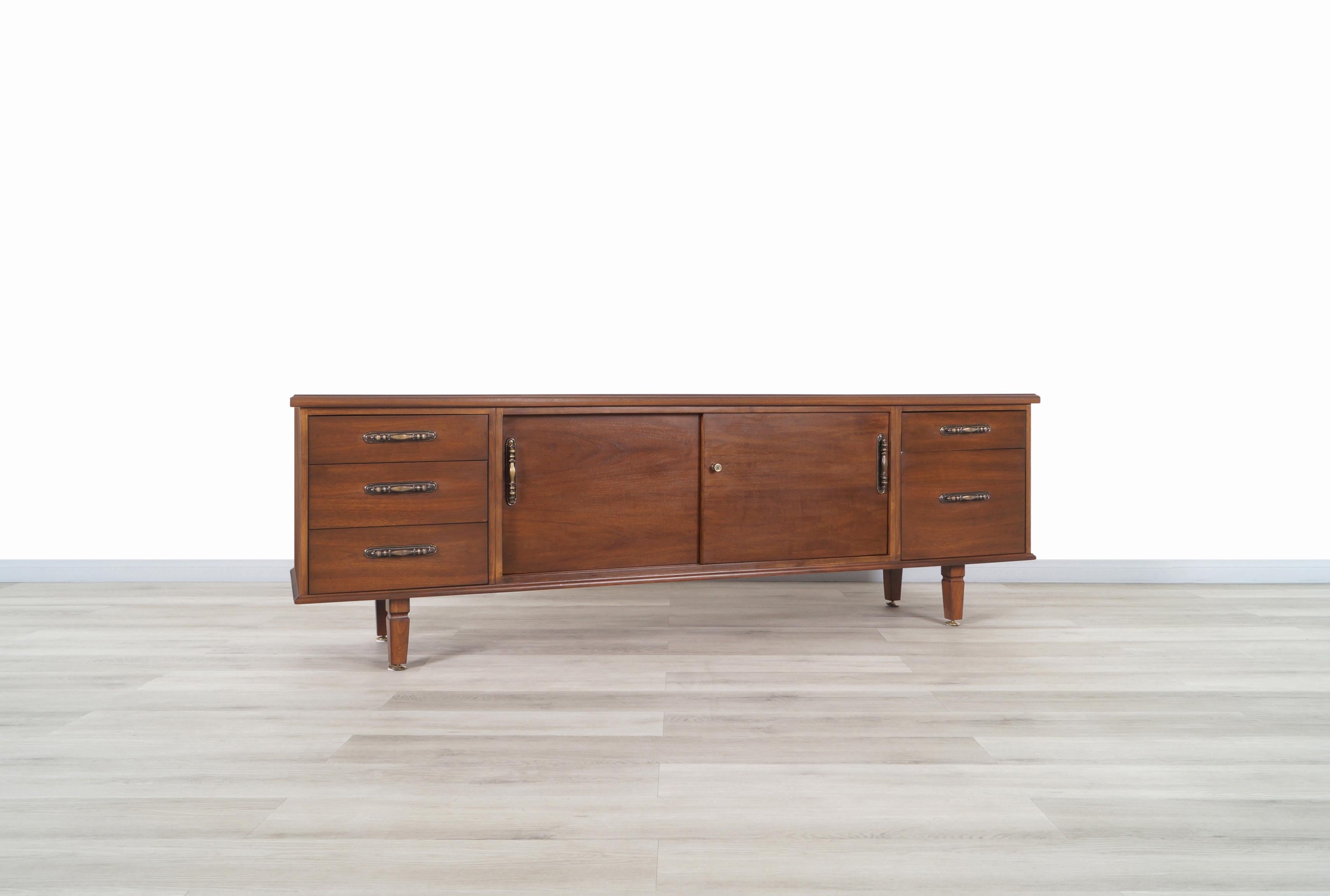 An elegant vintage walnut credenza designed by Maurice Bailey for Monteverdi Young in the United States, circa 1960s. This amazing credenza has two sliding doors with adjustable / removable shelves in addition to five drawers with side rails, which