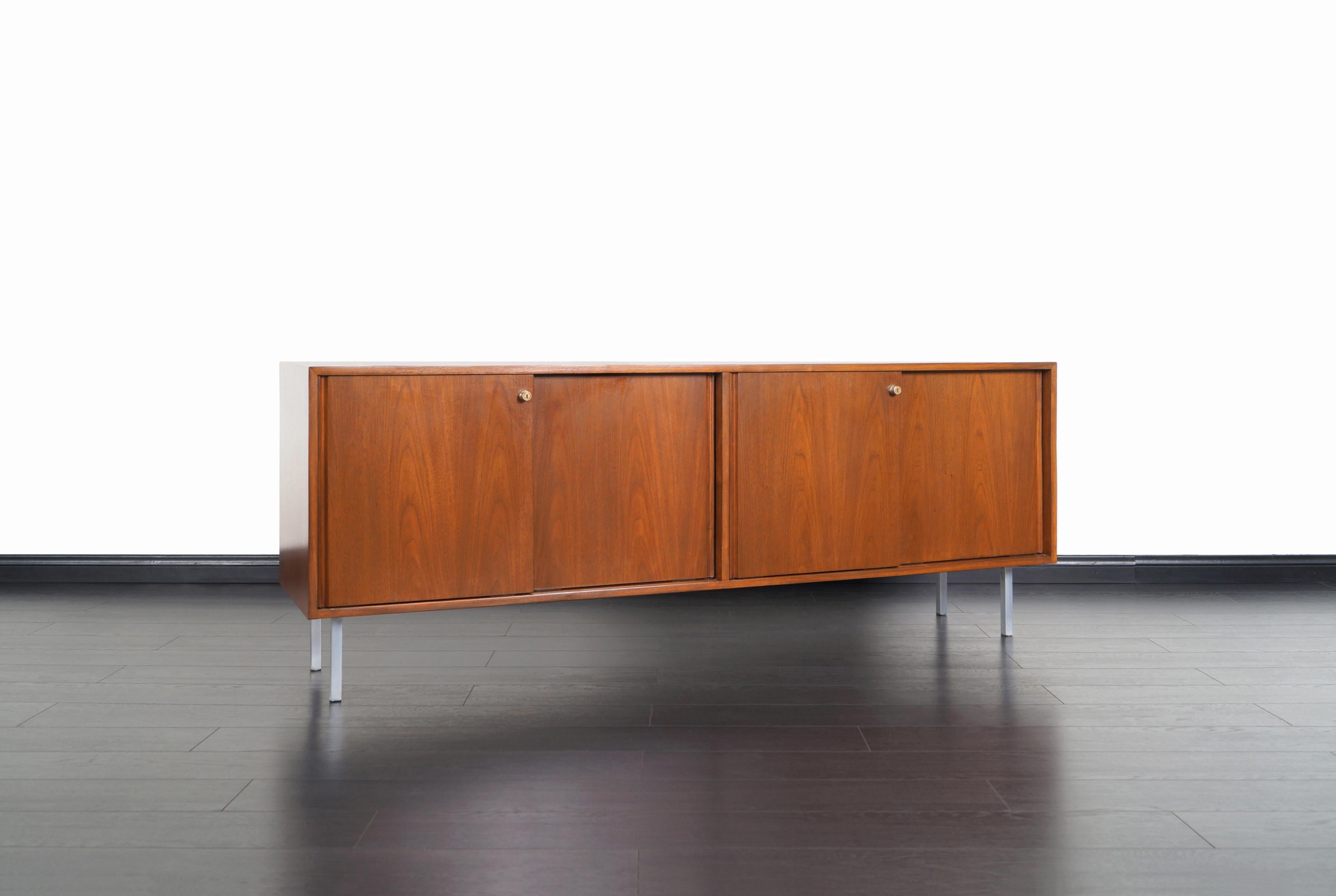 Gorgeous vintage walnut credenza in the manner of Florence Knoll in the United States, circa 1950s. Features a simple design in which the fine walnut grains that decorate the entire box stands out. In the front, there're four sliding doors with