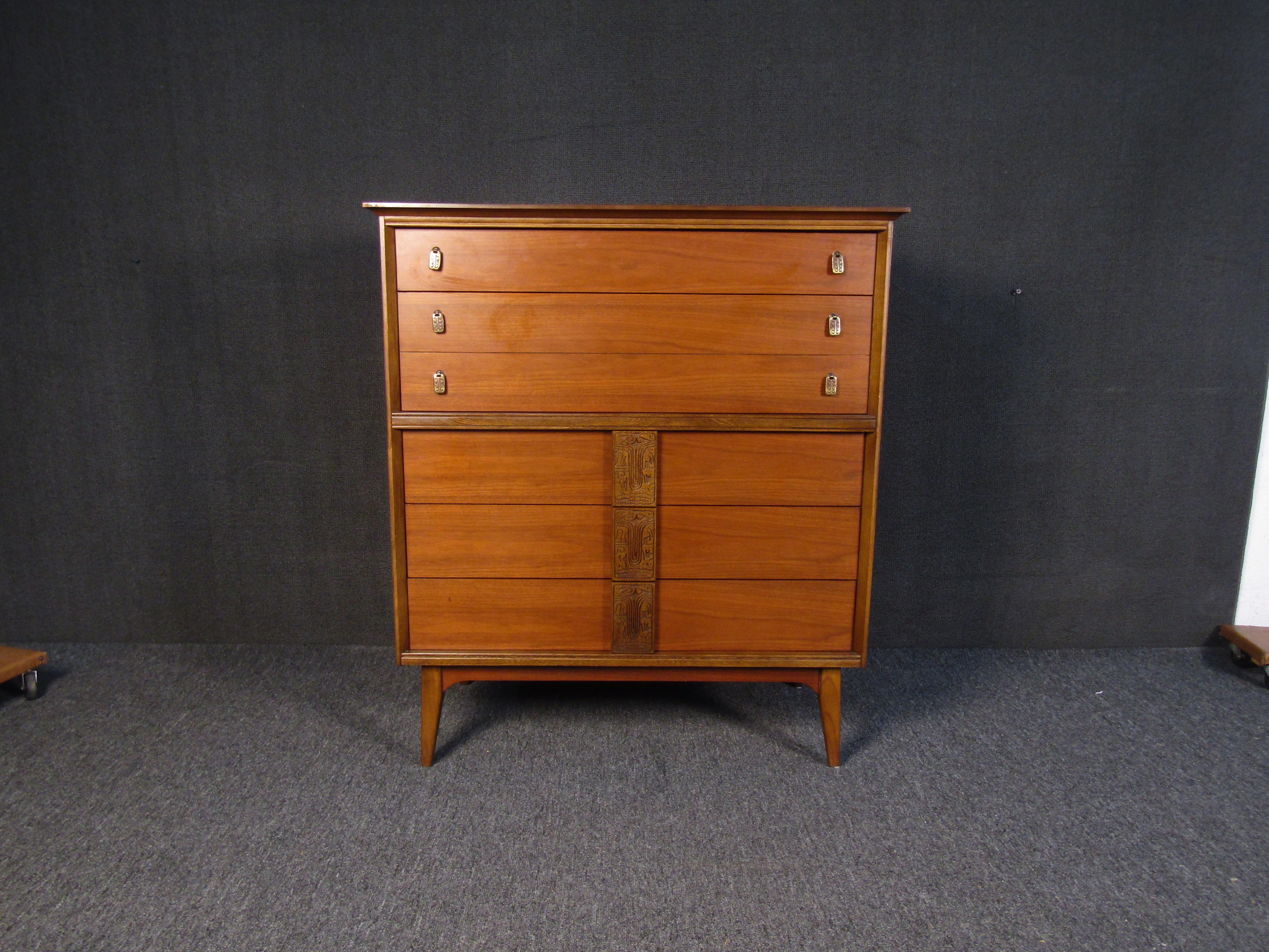 A large vintage dresser with sculpted wooden accents and metal drawer pulls. With a rich shade of walnut making this dresser attractive and versatile, it is a sure way to add Mid-Century Modern style to a bedroom. Please confirm item location with
