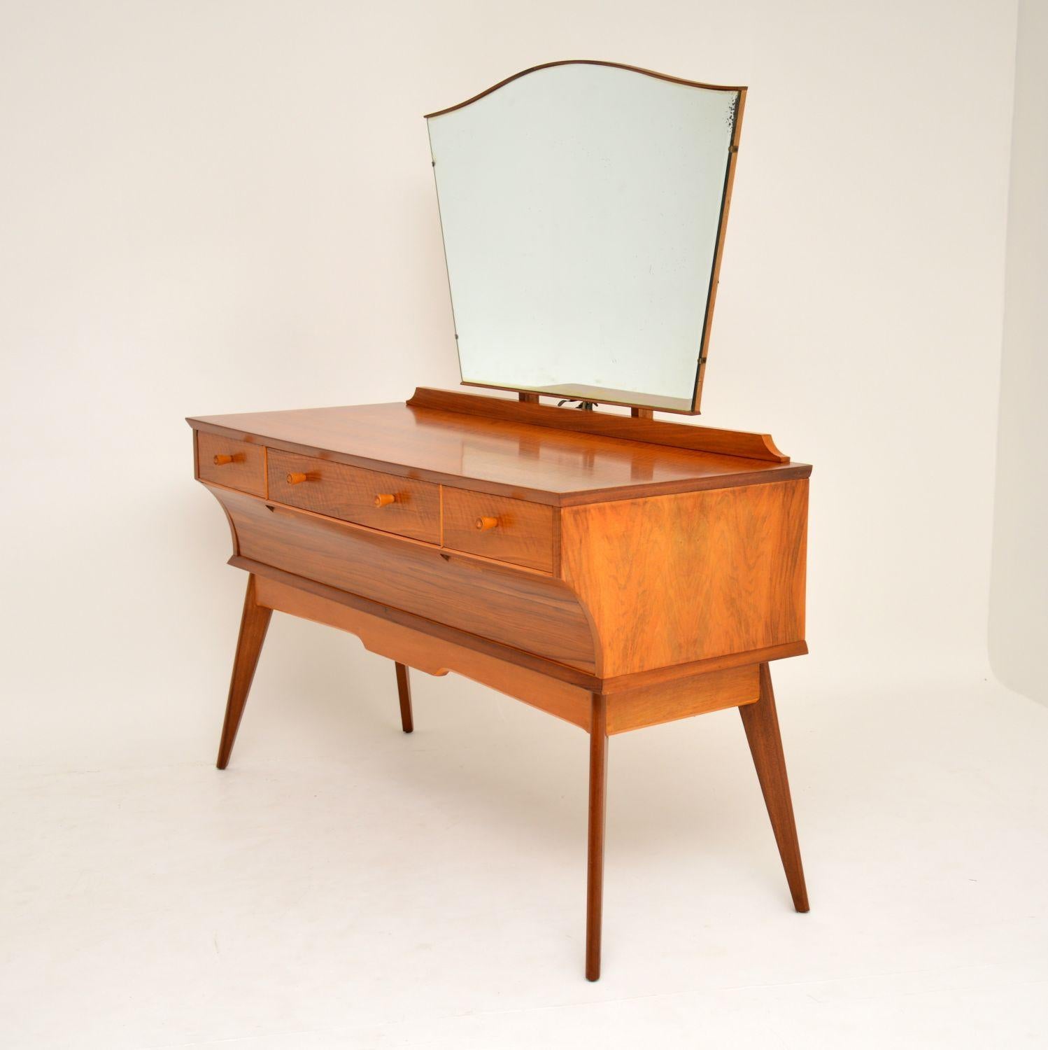 A beautifully styled vintage dressing table in walnut, made by the high end manufacturer Alfred Cox. This dates from the 1950-60’s and is in superb condition. We have had this fully stripped and re-polished to a very high standard. It sits on