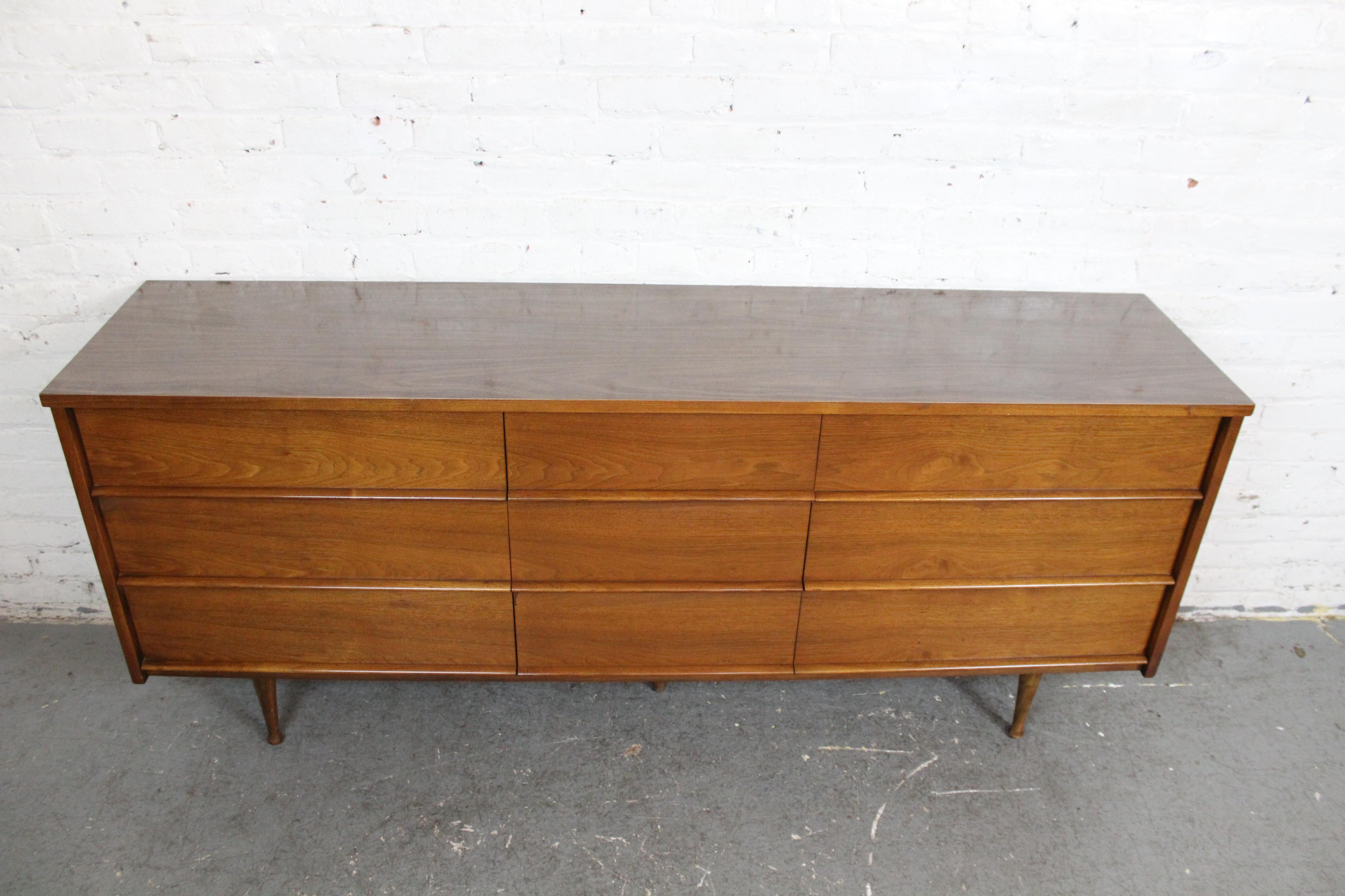 Bring home the subtle elegance and time-tested practicality of American Mid-Century Modern design with this vintage dresser made by Canterbury Fine Furniture for Plainfield, New Jersey's Thomas Furniture store. Boasting nine pull-out drawers in a