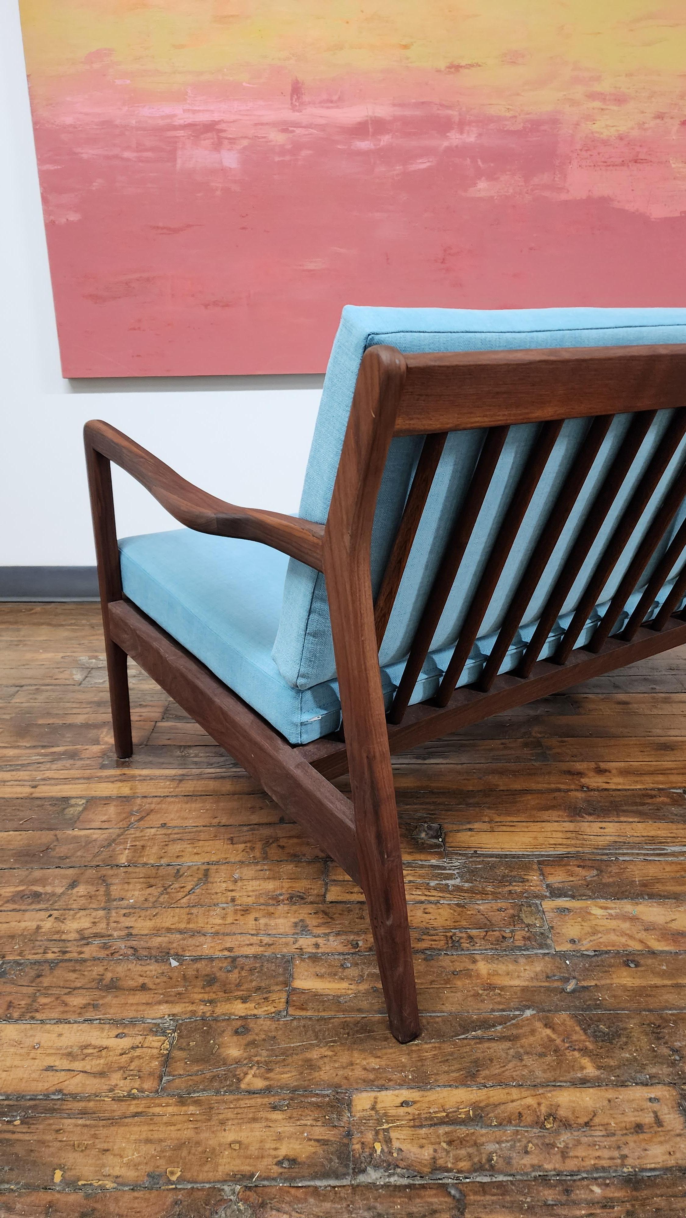 Beautiful walnut frame loveseat sofa in the style of Ib Kofod Larsen.  Features a refinished walnut frame with new webbing and fresh blue upholstery.   Its a classic danish modern design with striking lines.  unmakred.