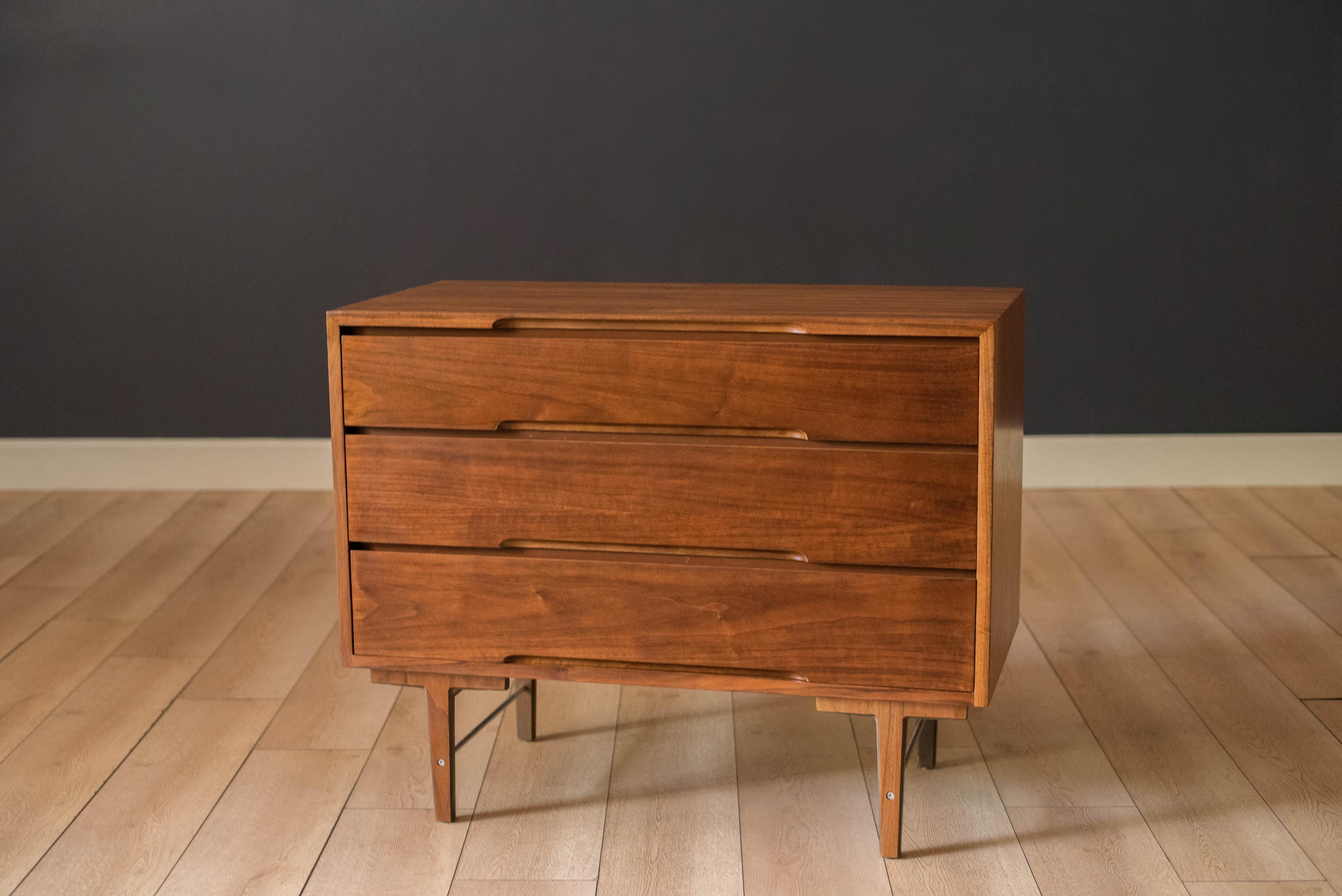 Mid century modern chest of drawers in walnut designed by Kipp Stewart for Glenn of California, circa 1950's. Features sculptural inset handles providing three storage drawers with dovetail construction. Supported by a unique base with two aluminum