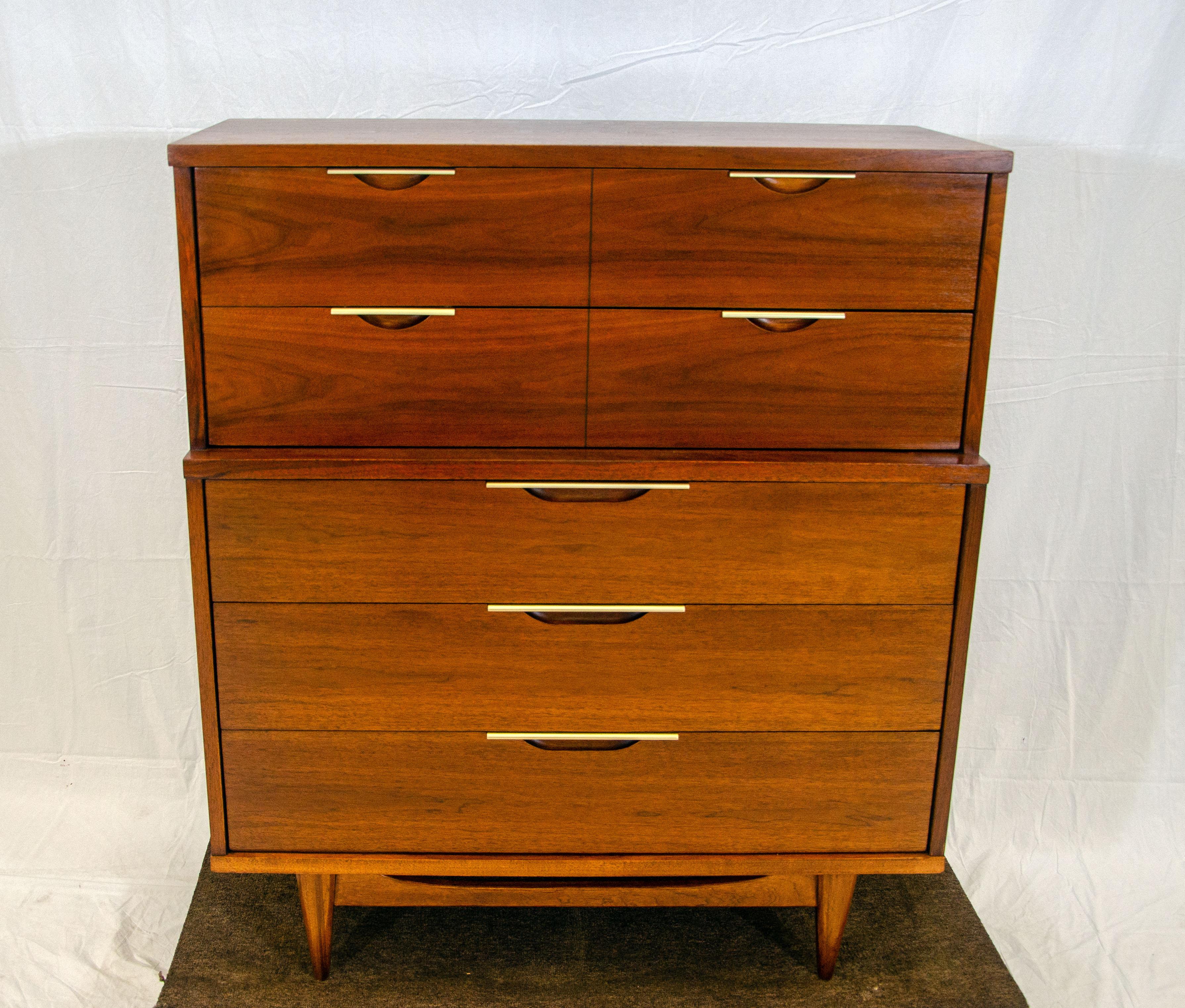 This very collectible line of Kent Coffey dressers is made of walnut with brass accents on the drawer pulls. The top section has a 2