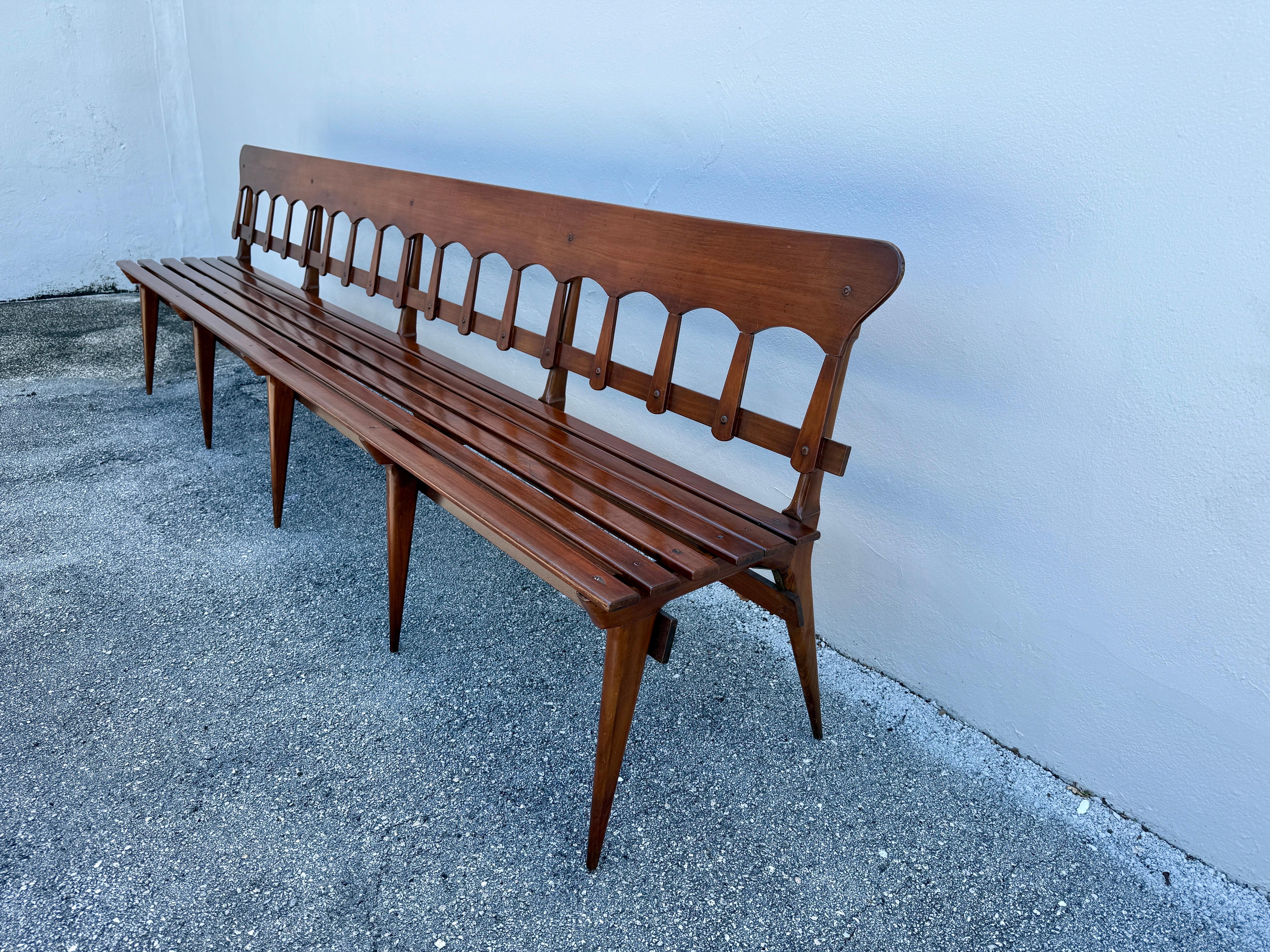 Diseño clásico italiano a la vista con estos preciosos bancos largos de galería en nogal.  Con finos detalles como las patas de sable y el respaldo festoneado, muy al estilo Ponti, este banco de madera de listones muy largos es ligero y, sin