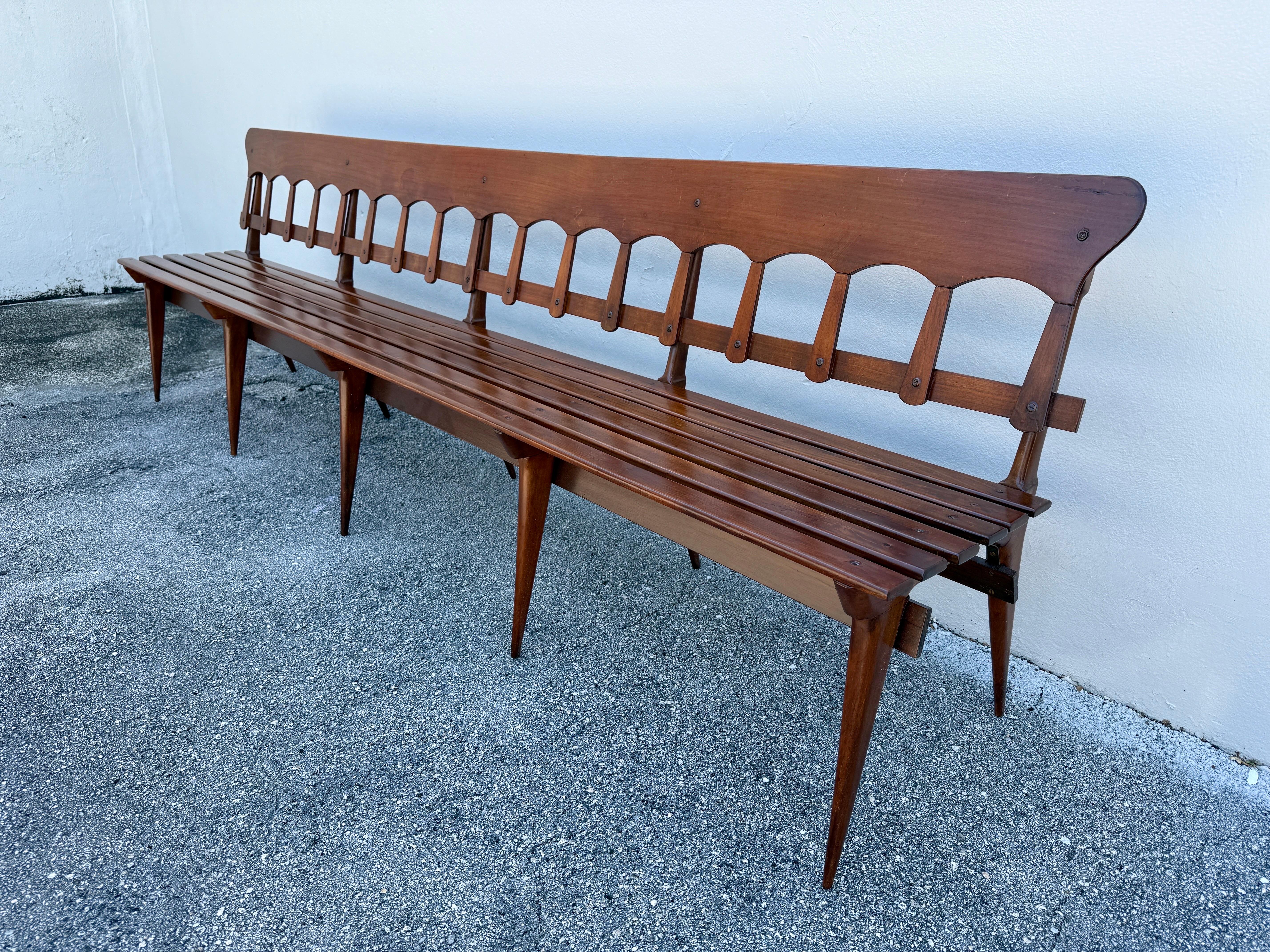 Classical Italian design on display with these beautiful long gallery benches in walnut.  Fine details such as saber legs and scalloped backrest, in the Ponti style, this very long slatted wood bench is lightweight and yet VERY sturdy.  We have two