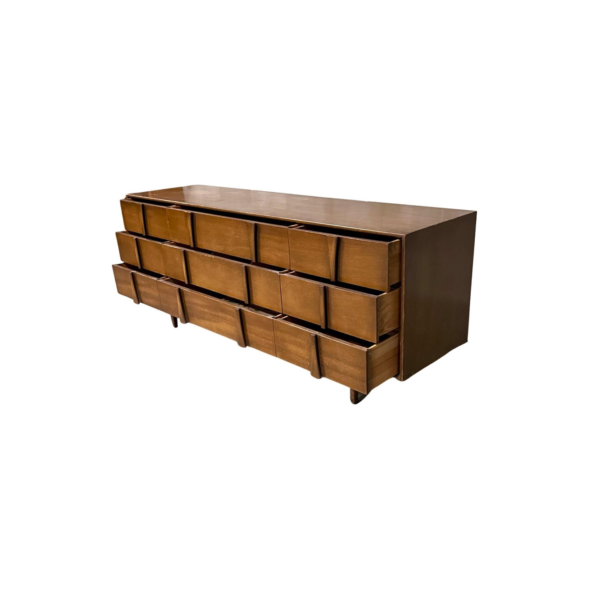 Check out this generously proportioned dresser, stretching an impressive 78 inches long and accommodating nine drawers. Crafted with utmost artistry, this vintage 1960s mid-century modern triple dresser showcases exquisite solid walnut sculpted