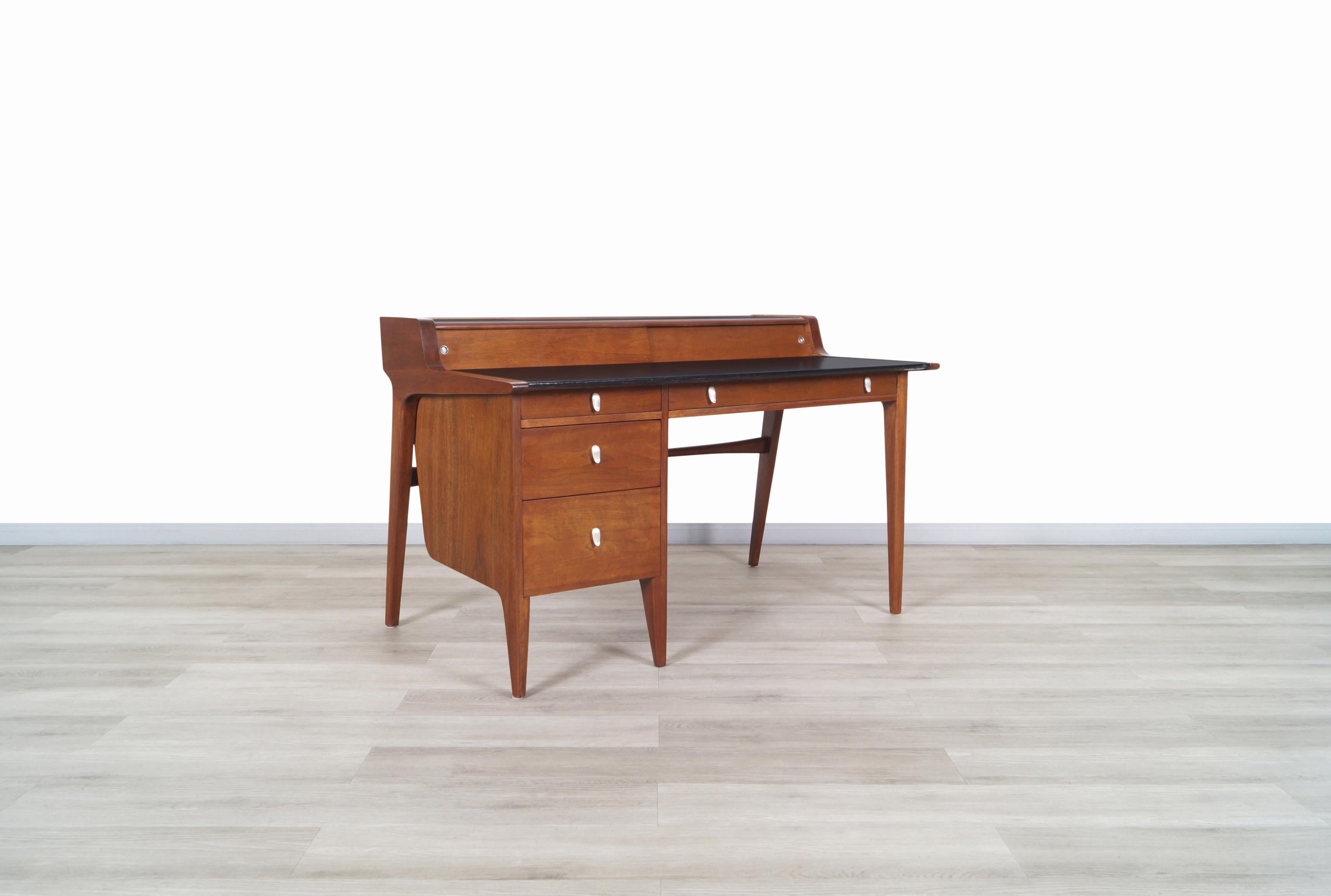 Stunning vintage walnut model-K80 executive desk designed by John Van Koert for the Drexel Profile series, circa 1960s. This desk has an elegant and versatile design, it is built with walnut wood where we can appreciate the fine details of the