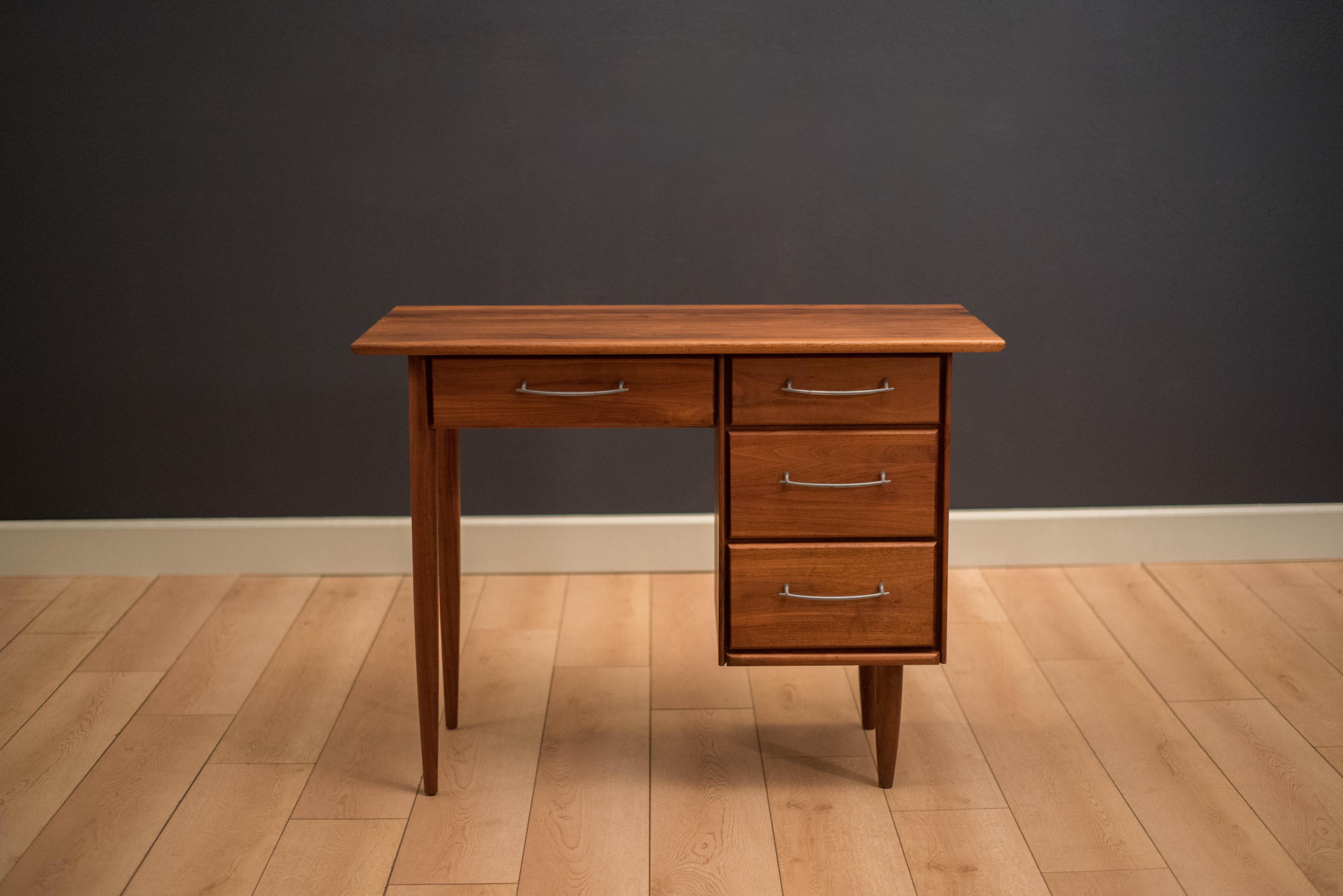 Mid-Century ACE-HI compact writing desk in solid planked walnut. This piece offers plenty of storage space complete with four drawers accessorized with pewter handles. Displays well from any angle and is finished on the back. 
 
Measures: Seat