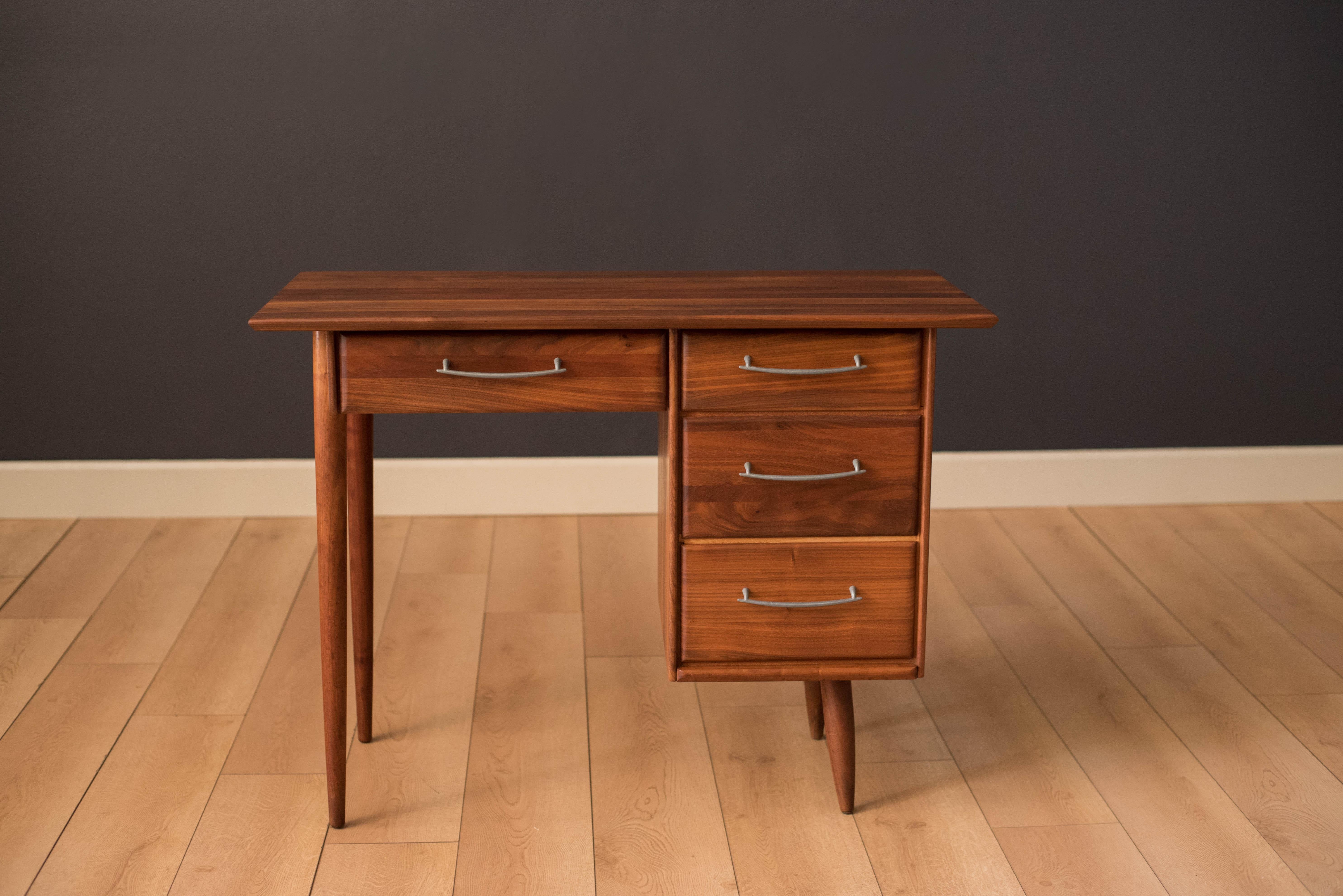 Mid century Ace-Hi compact writing desk in solid planked walnut. This piece offers plenty of storage space complete with four drawers accessorized with pewter handles. 

Measures: Seat opening 18