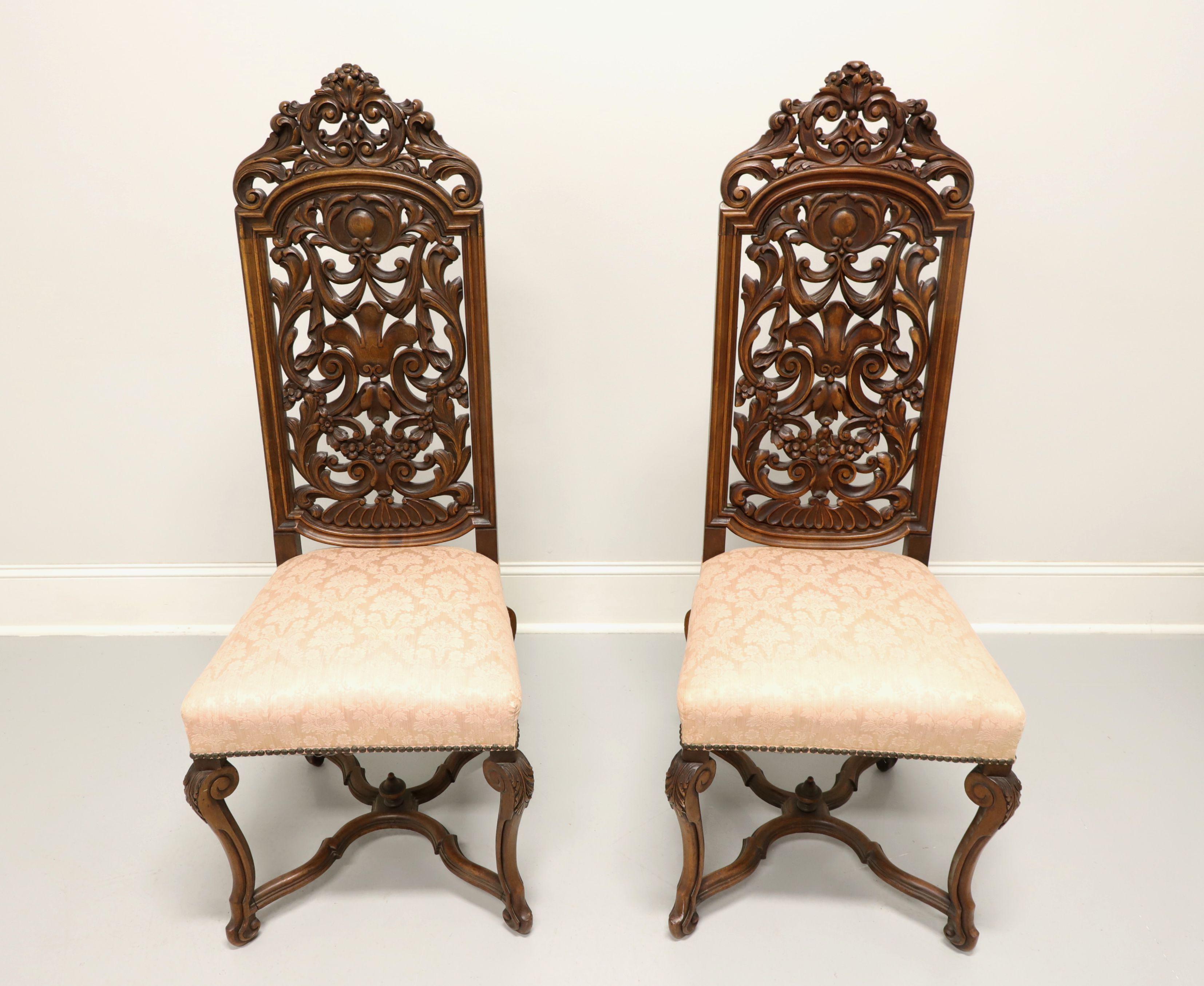 A pair of Renaissance Revival style side chairs, unbranded. Solid walnut with a tall, highly carved foliate design back, light pick color brocade fabric upholstered seat with nailhead trim, curved carved legs and carved stretchers with center