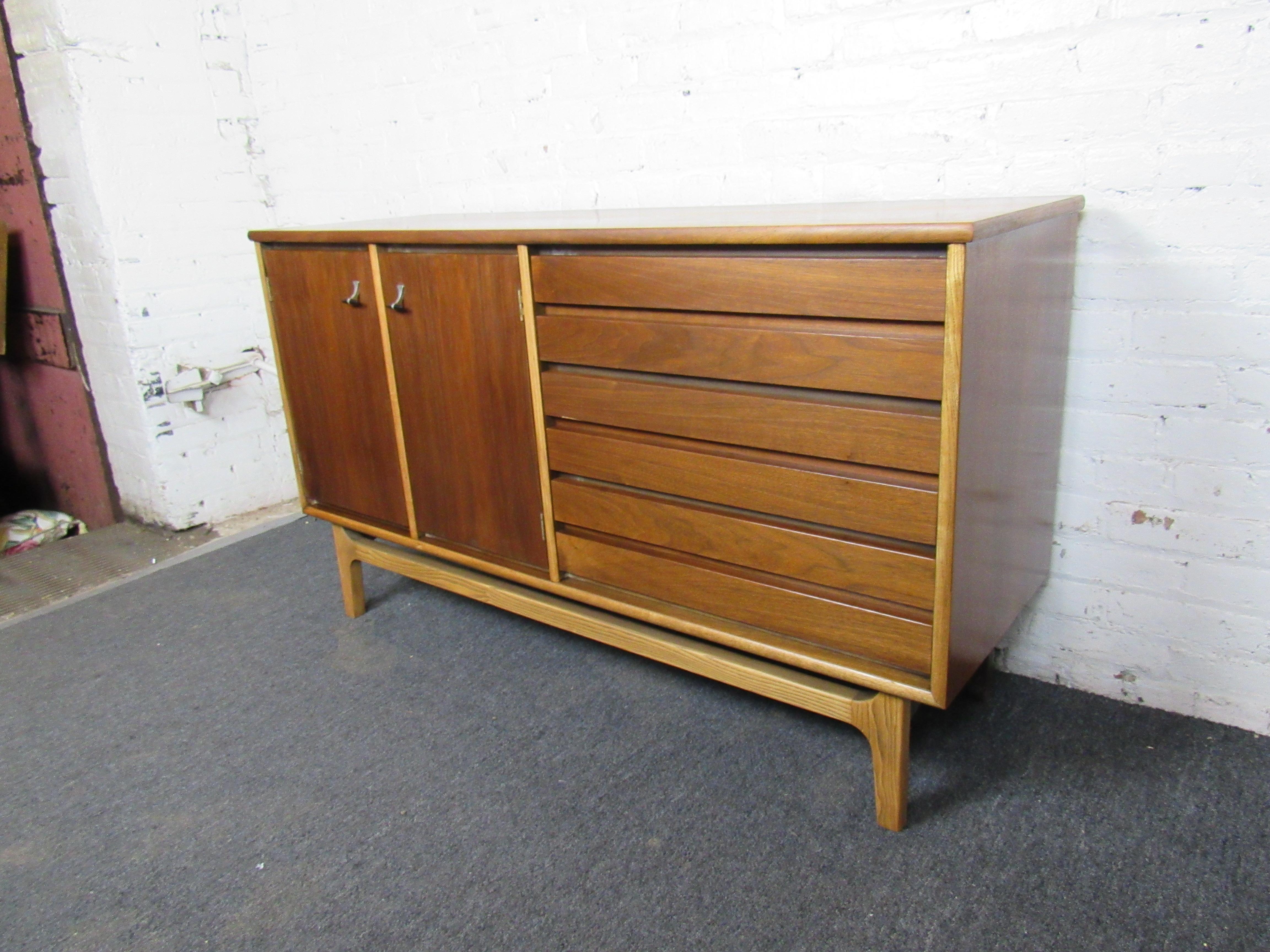 A gorgeous and understated vintage server displaying a rich walnut woodgrain and sculpted legs. With three drawers and storage compartments behind cabinet doors, this server offers plenty of storage space for its compact size. Please confirm item