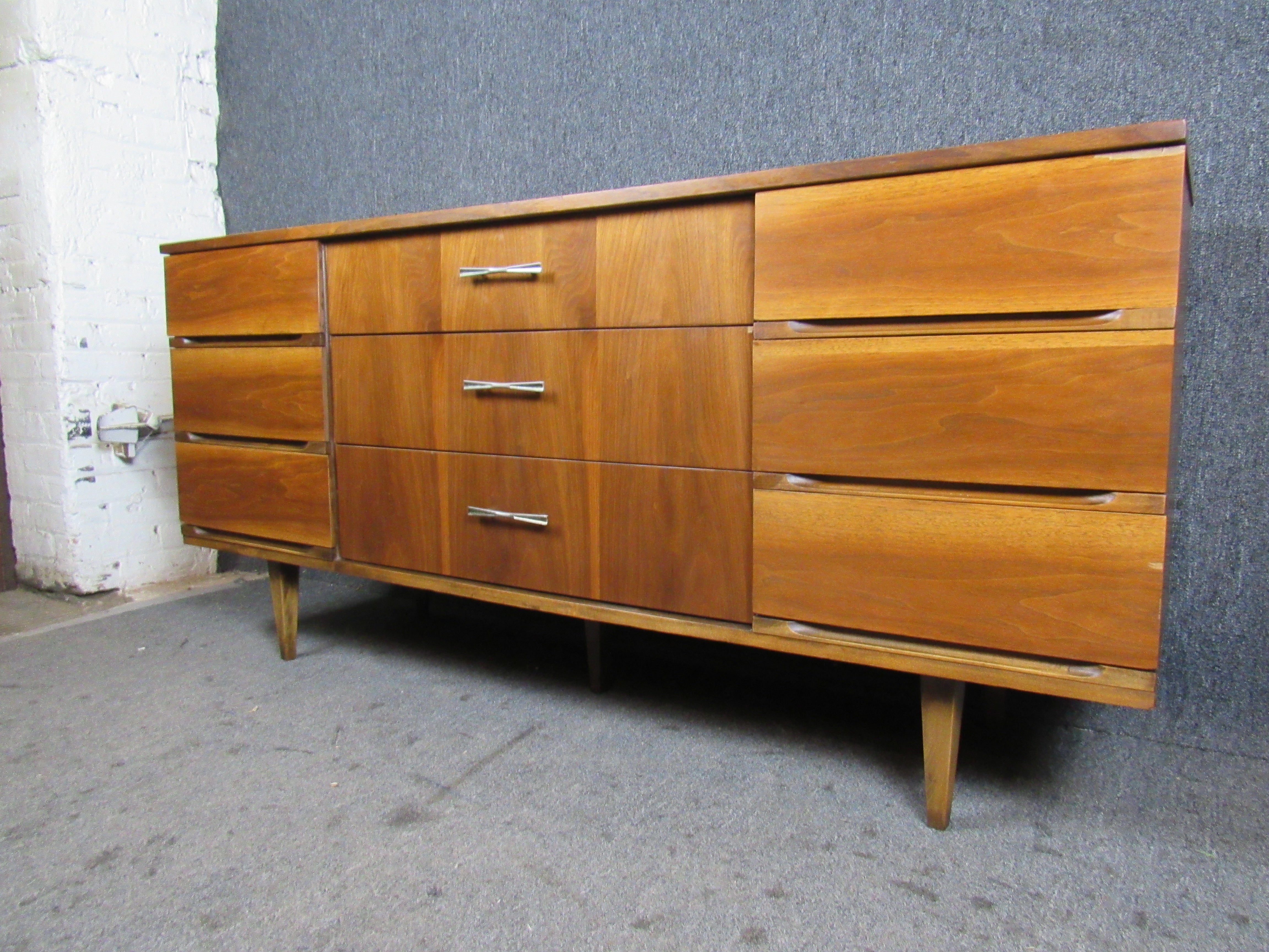 Lovely mid-sized vintage walnut credenza made by Harmony House for Sears Roebuck. Nine ample pull-out drawers feature stunning woodgrain that makes this dresser a statement piece for your home or office. Attractive bow tie handles sport authentic