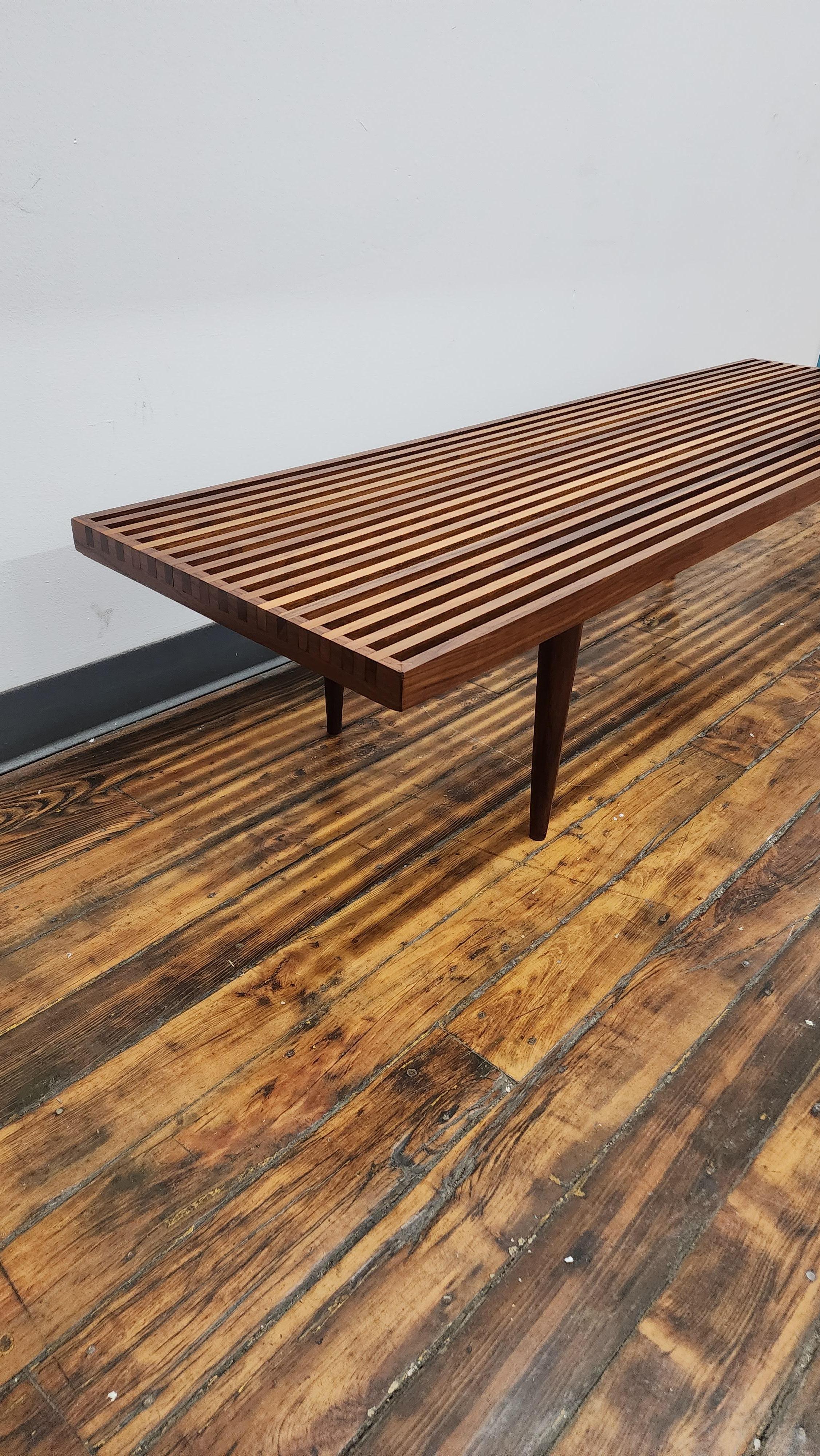 Banc à lattes en noyer magnifiquement travaillé par Mel Smilow.   Le design se caractérise par des pieds en noyer tournés et effilés et d'excellents détails sur l'extrémité montrant la boîte  les joints de fixation des lamelles. 