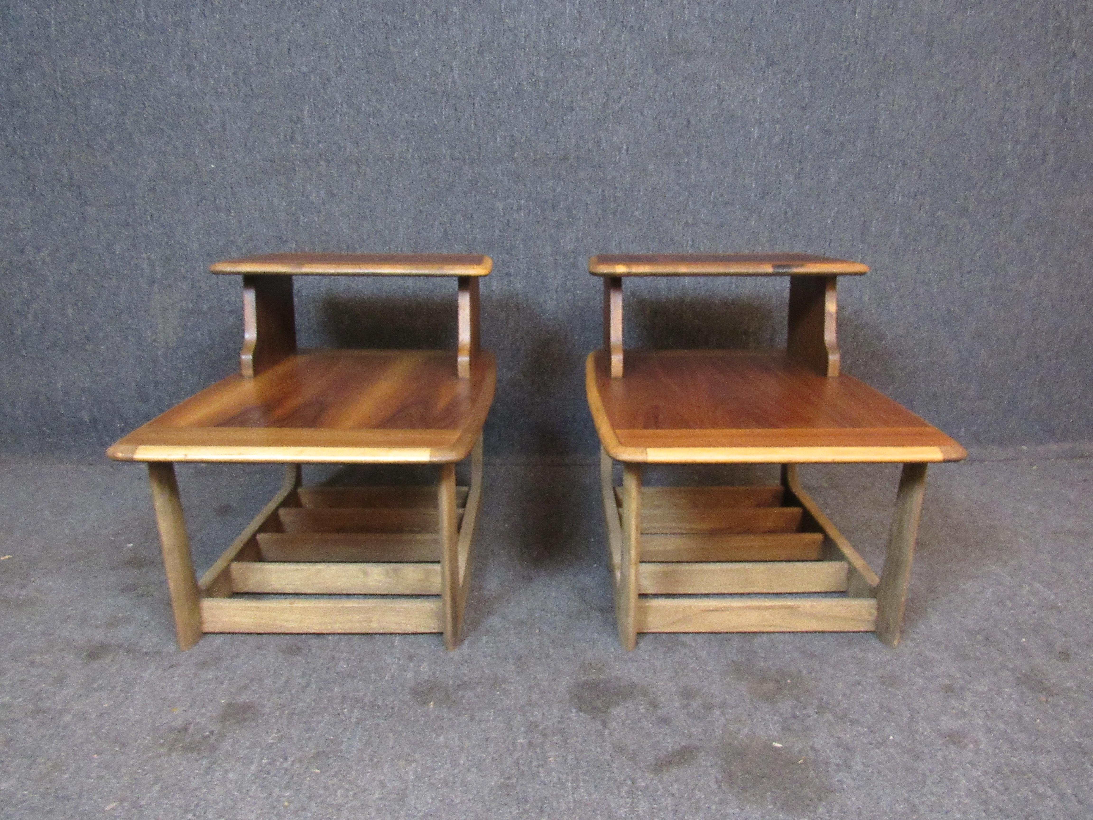 Fantastic pair of vintage step tables by the world-renowned craftsmen of Virginia's Bassett Furniture. Featuring gorgeously rich wood grains, sleek carved edges, a robust sled-leg base, and a convenient two-tiered design these tables offer as much