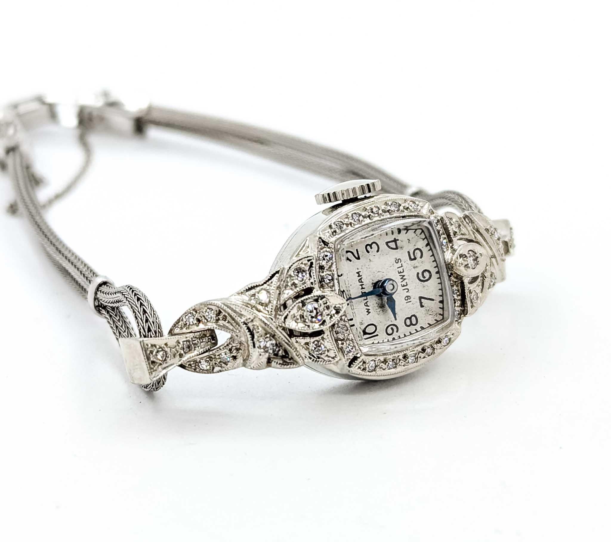This elegant vintage Waltham wristwatch is crafted in 14k white gold and set with sparkling diamond accents. The case and lugs feature intricate filigree-style detailing, adorned with approximately .20 carats total weight of single-cut diamonds that