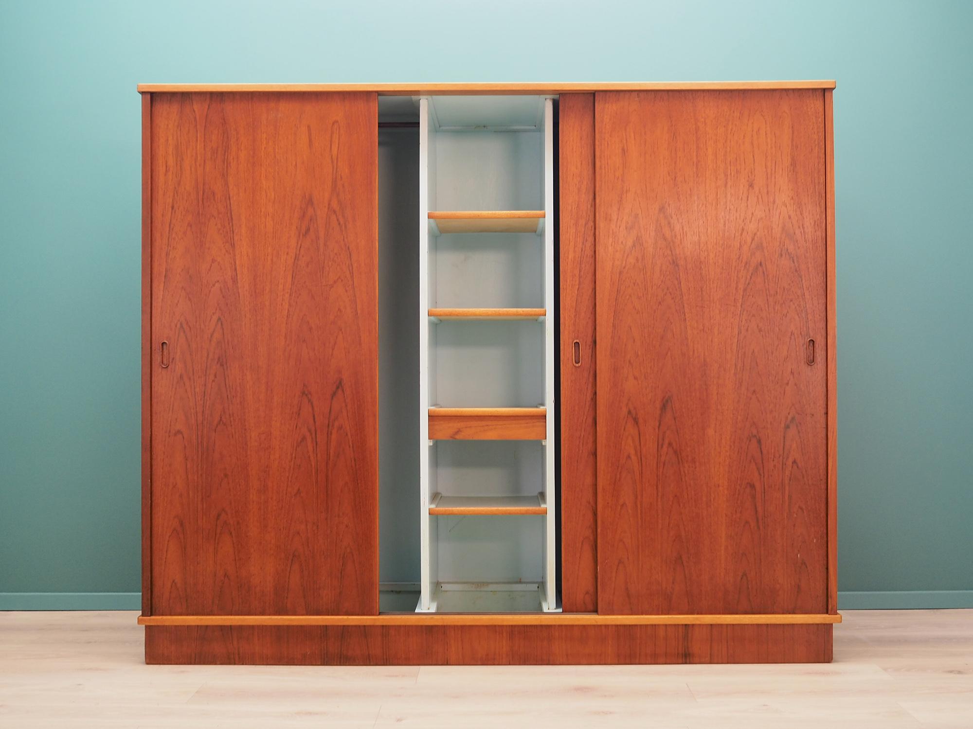 Extraordinary wardrobe from the 1960s-1970s, Scandinavian design, Minimalist form. Surface of the furniture is covered with teak veneer. Wardrobe has a spacious interior divided by four shelves, all located behind a sliding doors. Preserved in good