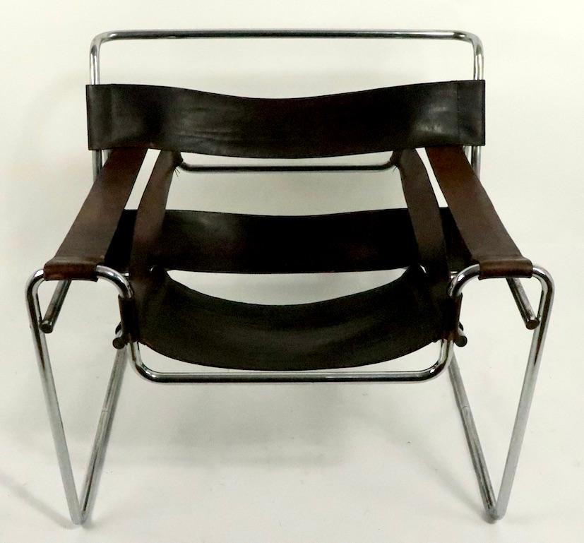 Nice early Wassily chair in rich brown patinated leather and chrome. This example shows some cosmetic wear, notably significant wear to chrome elements which run front to back, under the leather arm strap (see images). Unsigned, attributed to Knoll,