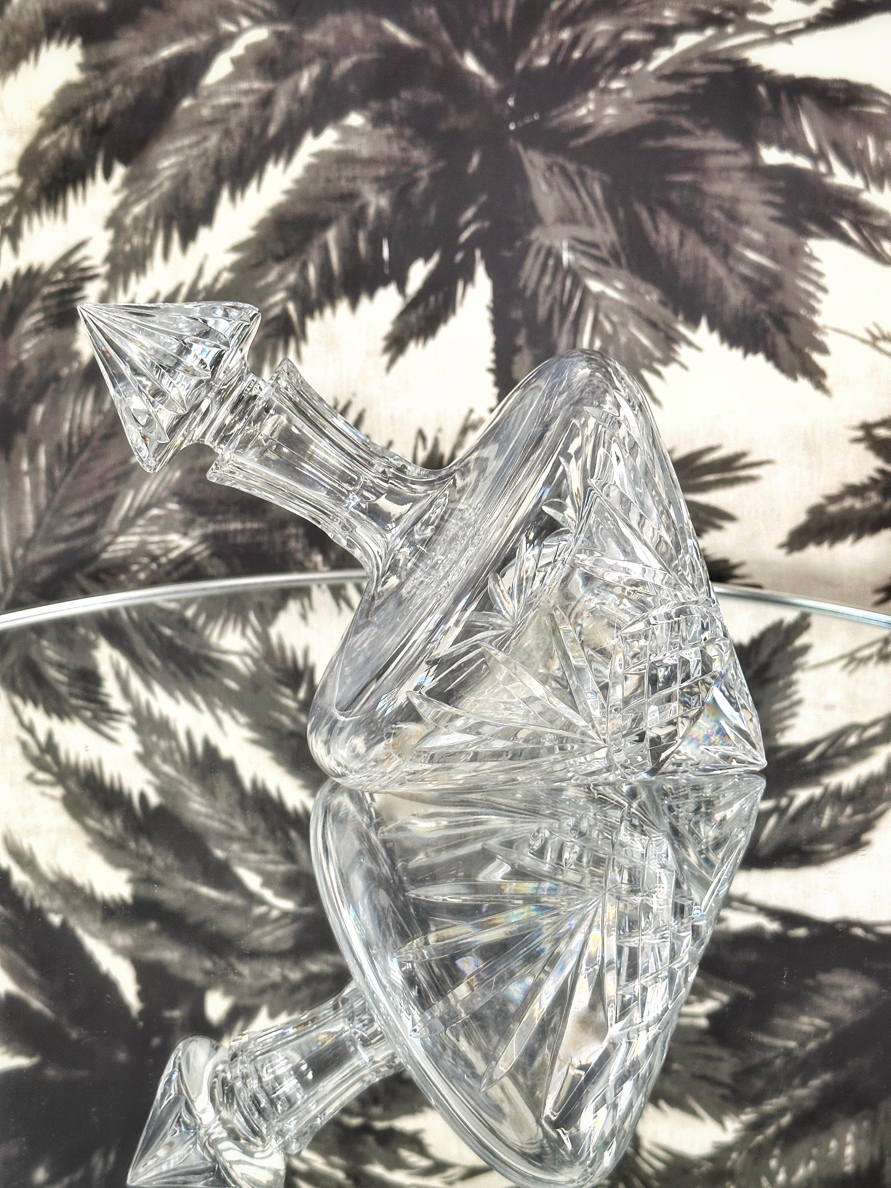 Stunning vintage tilted spirits decanter by Waterford Crystal. Handcrafted and mouth-blown lead crystal featuring brilliant prismatic diamond cuts with etched designs throughout. Also features fluted accents along the stem and is fitted with pointed