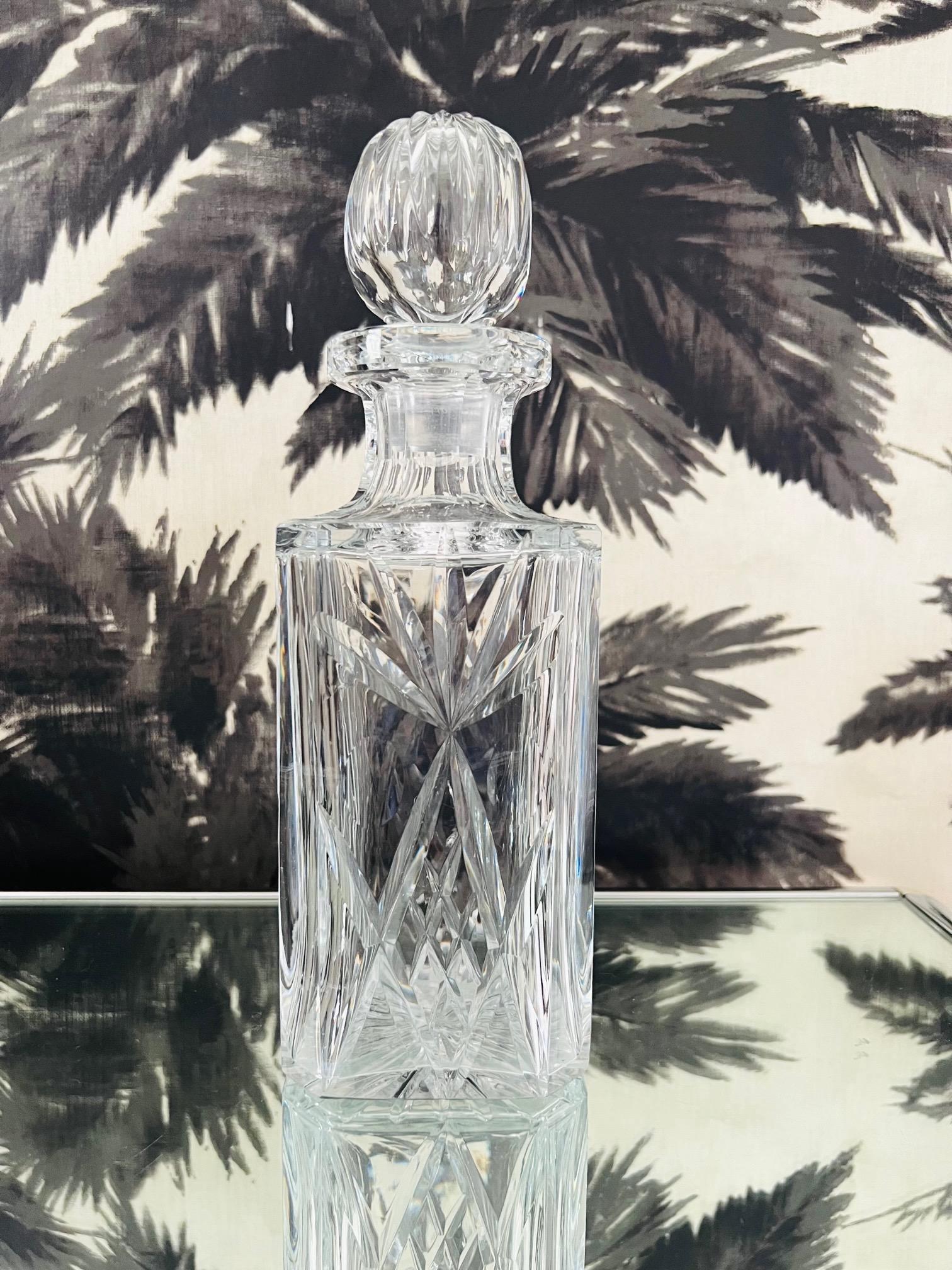 Elegant mouth blown and hand-cut crystal whiskey decanter by Waterford Crystal. The decanter has a square form with etched starburst designs, etched diamond cuts, and faceted crystal stem. Includes a stylized crystal ball stopper with etched