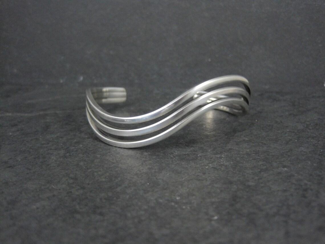 Este precioso brazalete vintage es de plata de ley.
Mide 7/16 de pulgada y se estrecha hasta 1/4 de pulgada y tiene una circunferencia interior de 6 1/2 pulgadas incluyendo el hueco de 1 1/4 pulgadas.
Peso: 21.4 gramos
Marcas: 925
Estado: Excelente