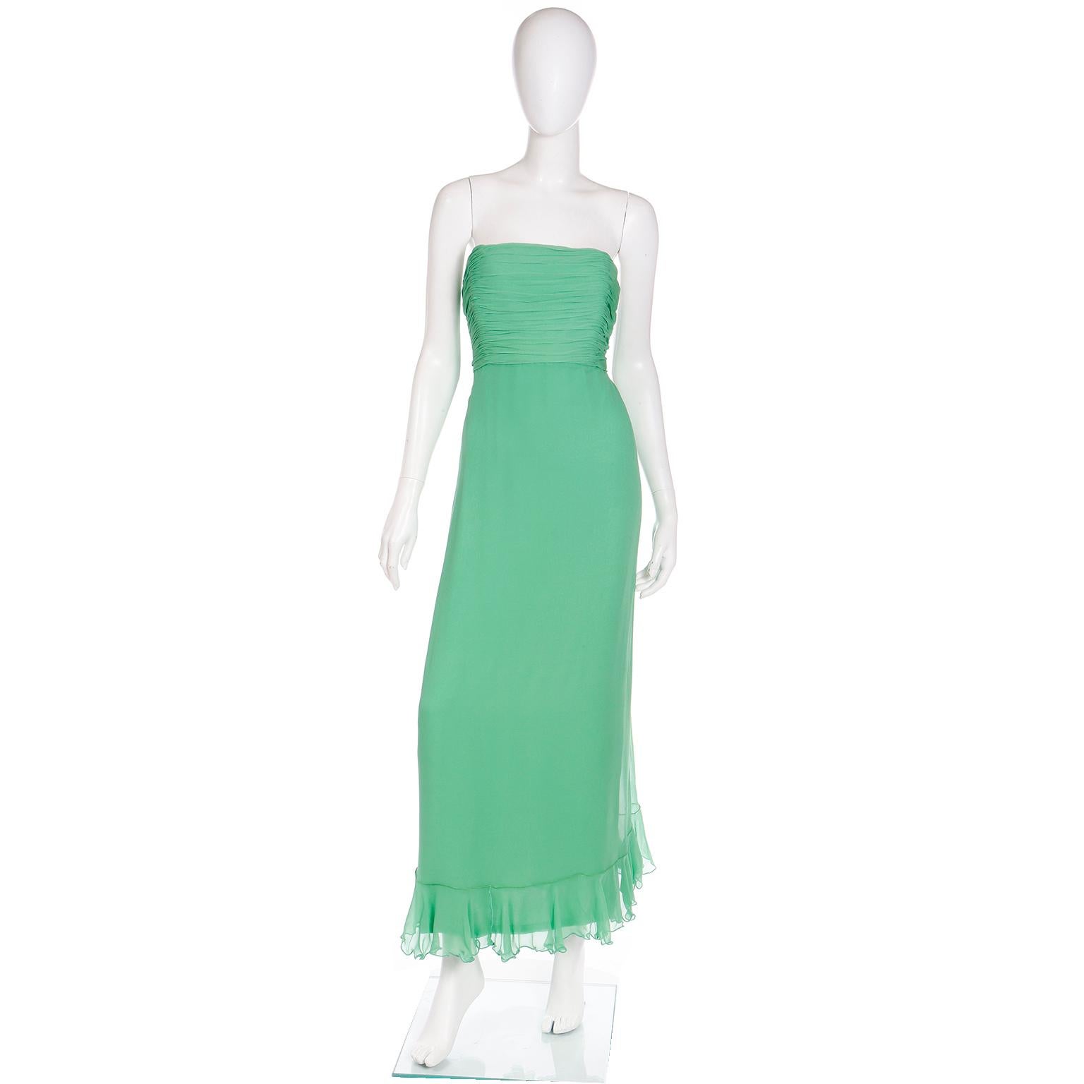 Dieses elegante, bodenlange Kleid aus grünem Seidenchiffon von Wayne Clark wurde in der Couture-Boutique Harriet Kassman in Washington DC gekauft. Das Kleid ist trägerlos, hat ein gerafftes Mieder und wird mit einem Rüschenschal geliefert, der auf
