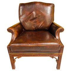 Fauteuil club vintage en cuir brun foncé patiné par les intempéries, de style classique
