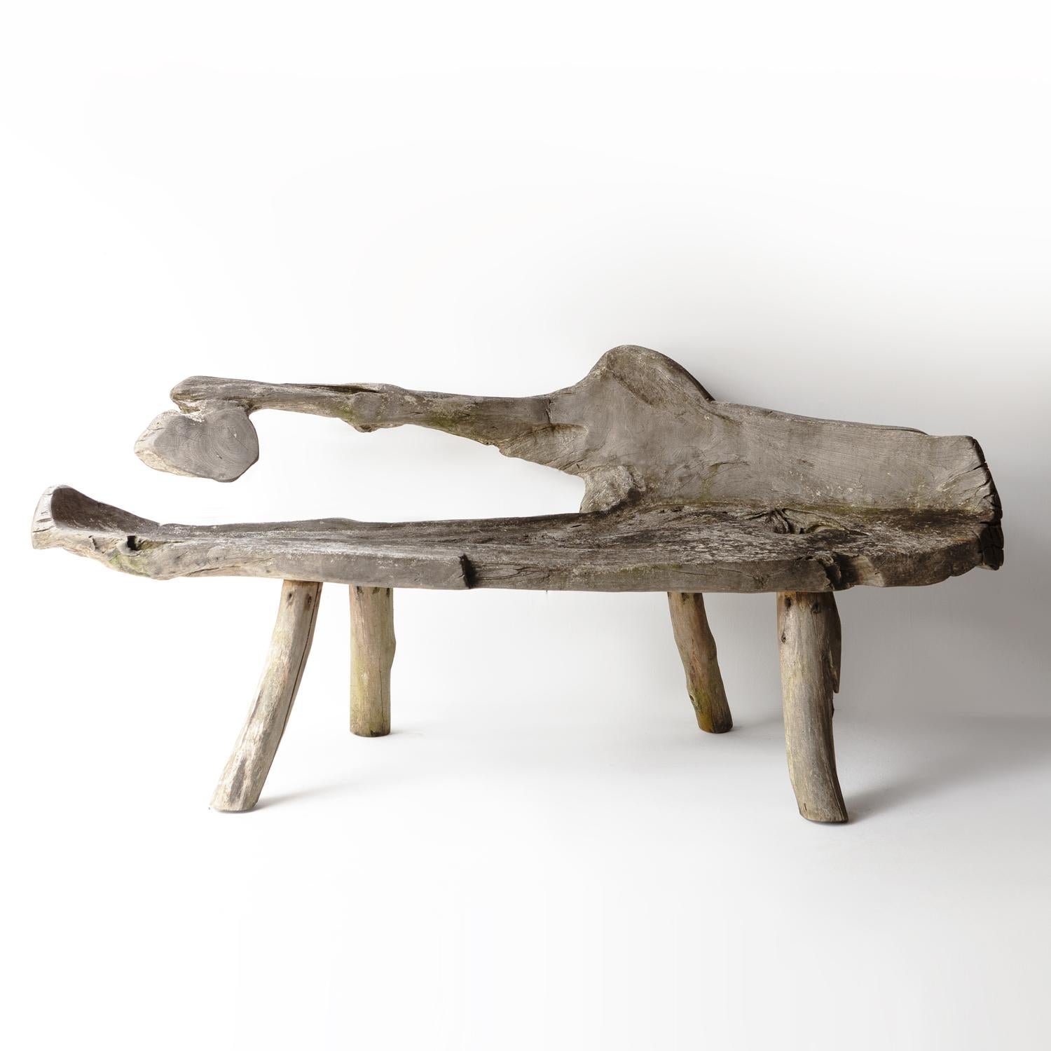 VINTAGE HARDWOOD BENCH 

Of primitive organic form utilising the natural shape of the ancient teak root. The seat and back are all one solid piece of timber which is gnarled and twisted in only the way that nature can produce. 

On four naively cut