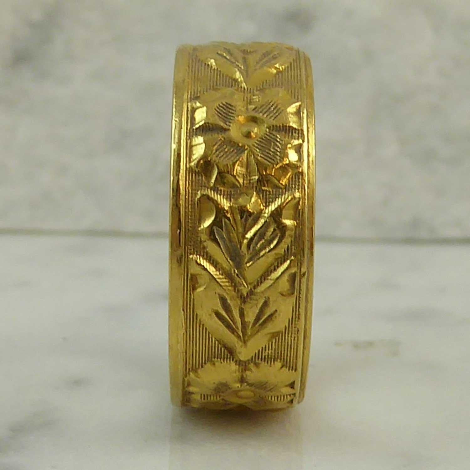 This is a marvellous vintage wedding ring from the 1960s.  Measuring approx. 0.32 inch wide, the ring has a flower and leaf design very nicely engraved all around against a hatched patterned backgound with a plain polished line to each edge of the