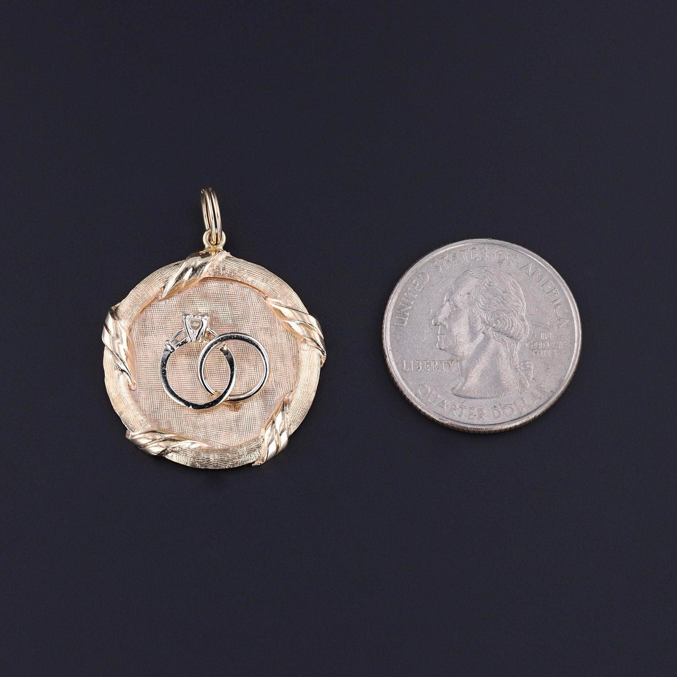 Questo ciondolo d'epoca in oro 14k (1950-1960 circa) presenta due fedi in oro bianco 14k con un singolo diamante.

Il pezzo misura 1,4 pollici dalla parte superiore della cauzione a quella inferiore e 1,1 pollici di larghezza ed è in ottime