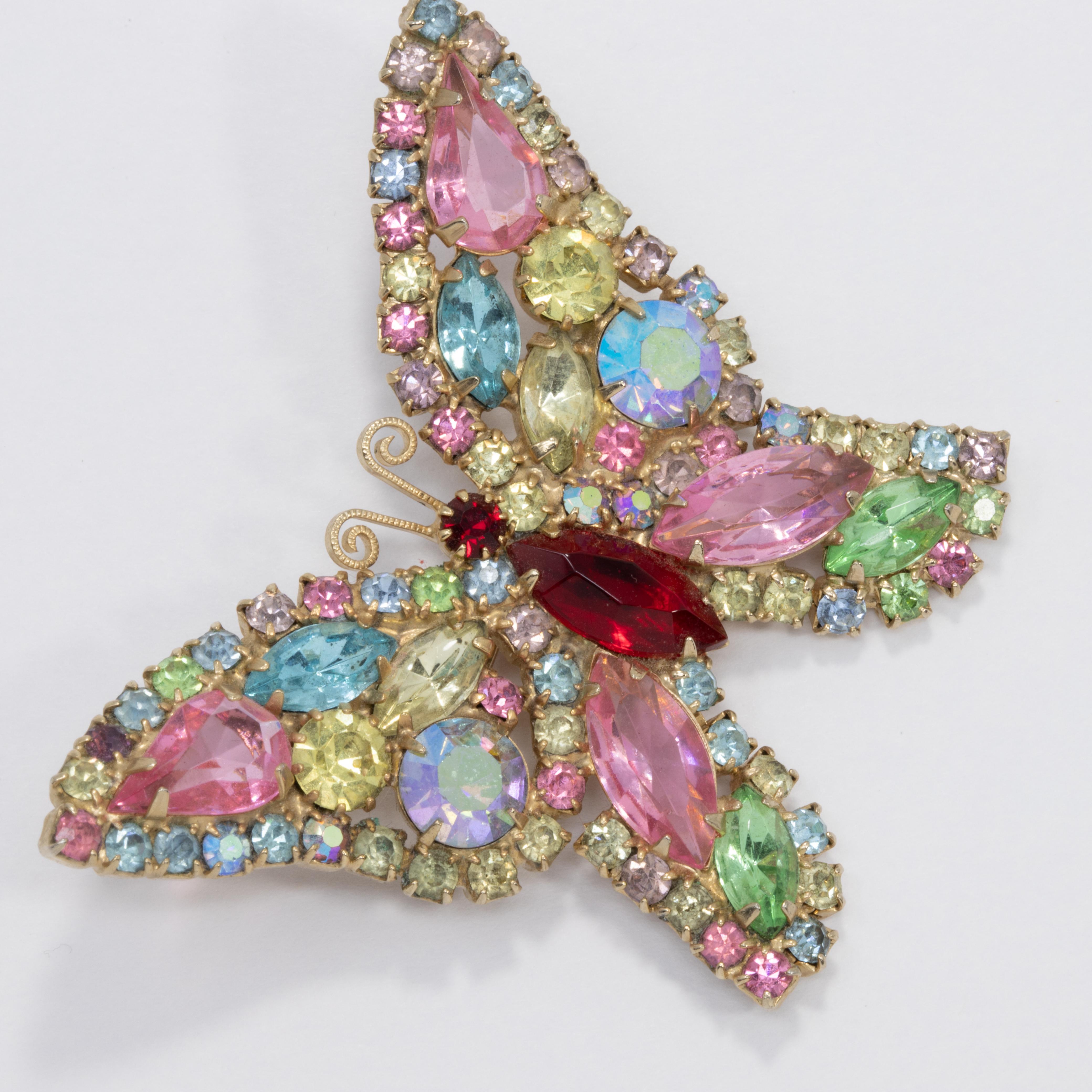 A sparkling butterfly pin brooch decorated with dazzling, prong set crystals. Features glittering peridot, rose, aquamarine, rose, and amber colors on a gold-tone setting.

Hallmarks: WEISS