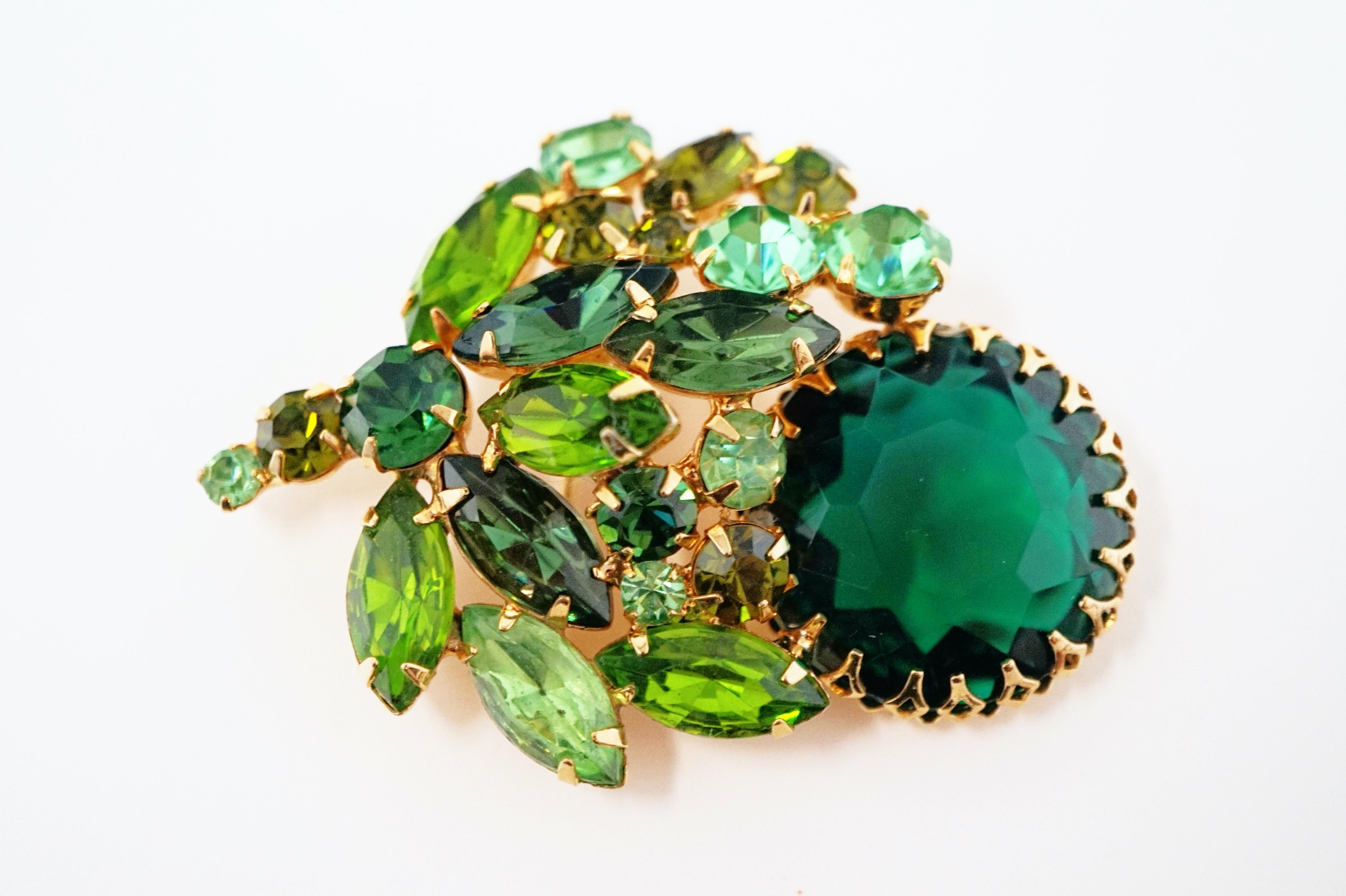 Absolutely stunning three dimensional statement brooch by iconic mid-century costume jewelry brand Weiss, circa 1950s. This piece is composed of sparkling Emerald and Peridot green colored crystal rhinestones prong set in gilded hardware. This