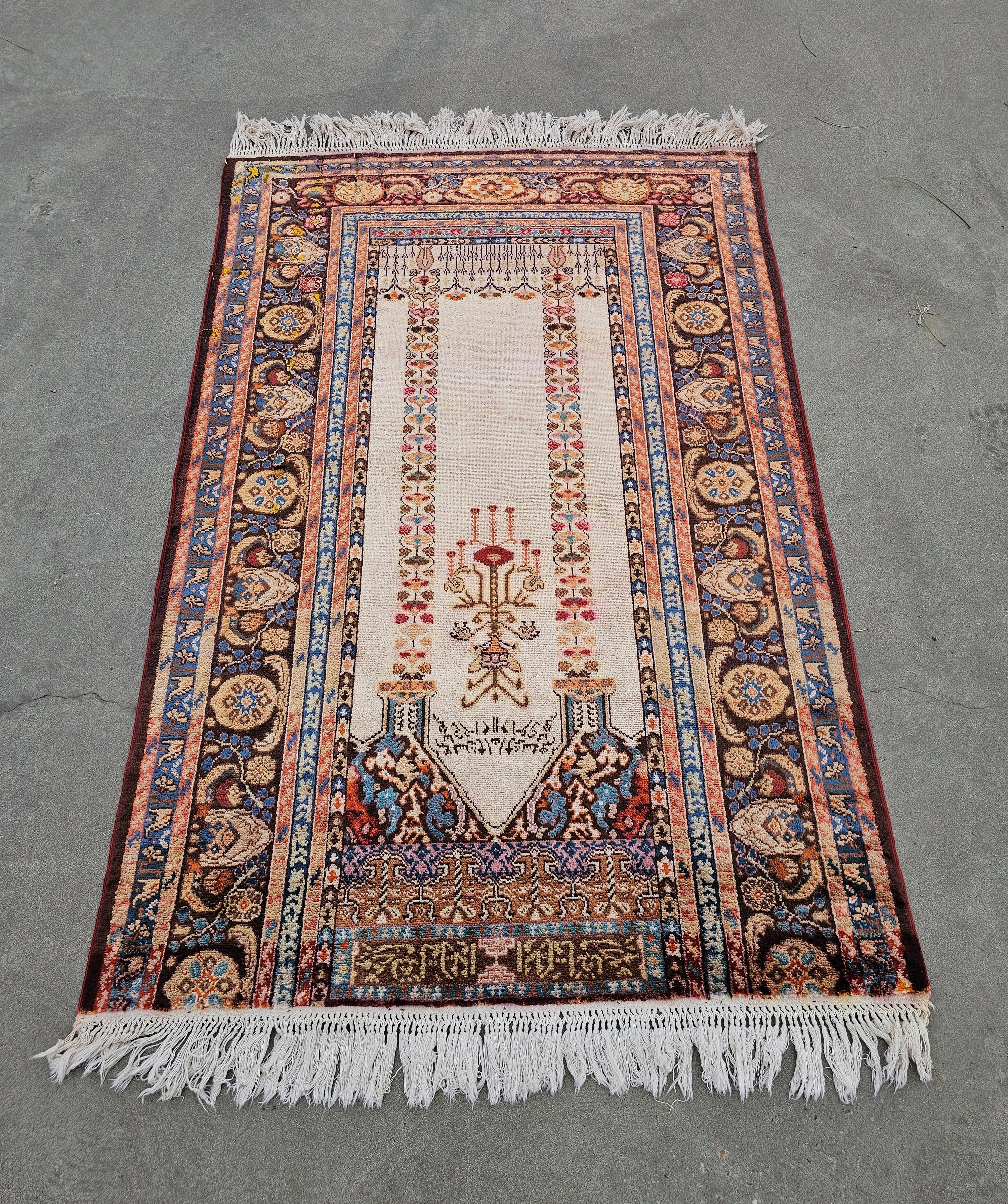 In this listing you will find a spectacular vintage Western Anatolian hand-knotted silk prayer rug. This Panderma rug features a Mihrab design pattern, with writings, and beautiful colors of cream, purple, burgundy blue and orange, is hand-knotted