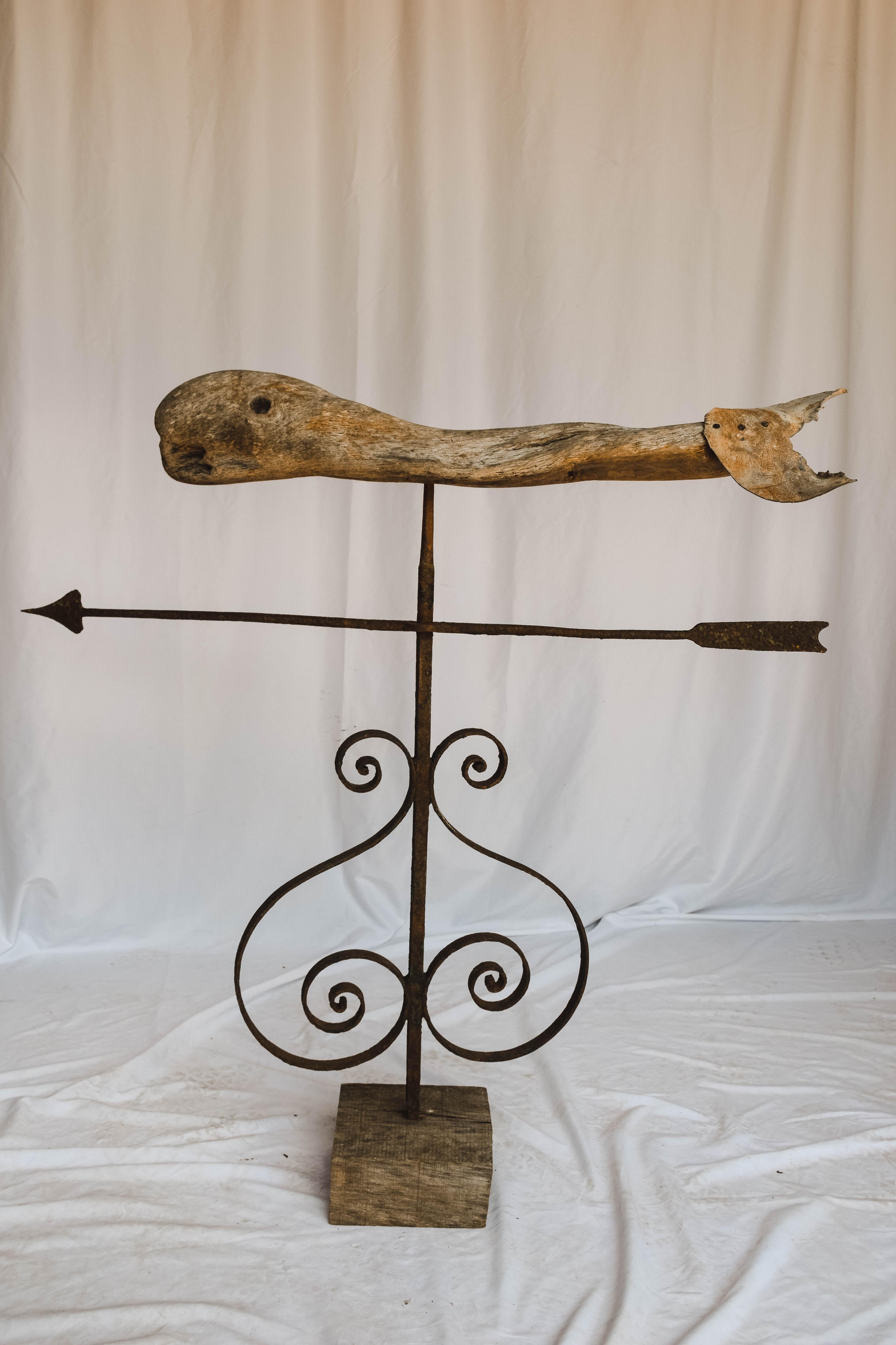 This wonderful vintage whale weather vane has a fantastic aged patina. The rustic wooden whale sits on a custom wood base attached by a metal rod with a Directional arrow and scroll work. Truly a fabulous decorative piece. We found this weathervane