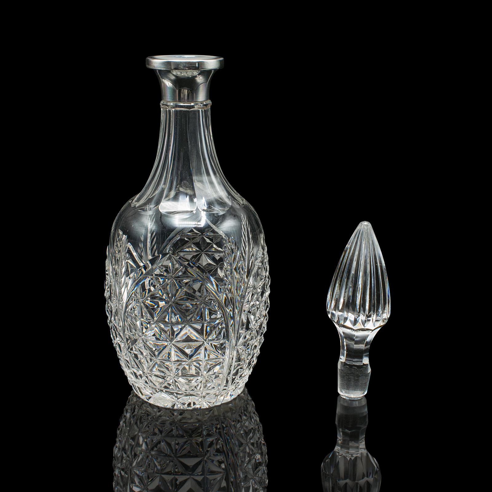 
This is a vintage whiskey decanter. An English, cut glass and silver spirit vessel, hallmarked to 1986.

Appealing form and finish with the brilliance of a silver collar
Displays a desirable aged patina and in good original order
Quality cut glass