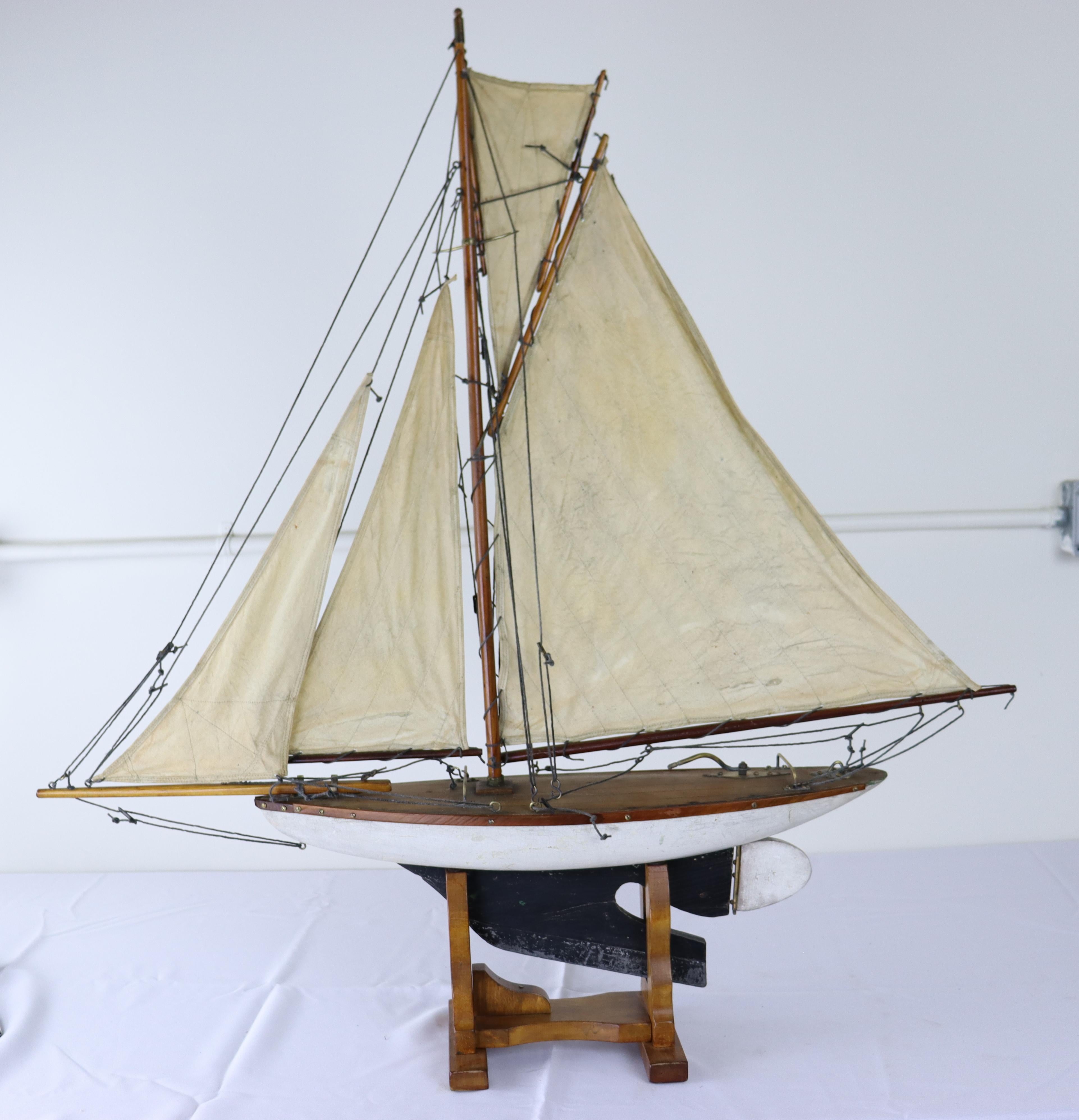 A charming vintage model yacht with sails made from old sail cloth and original brass accents. Stand is recent to hold the ship upright and stabile.  Measurements include the stand.