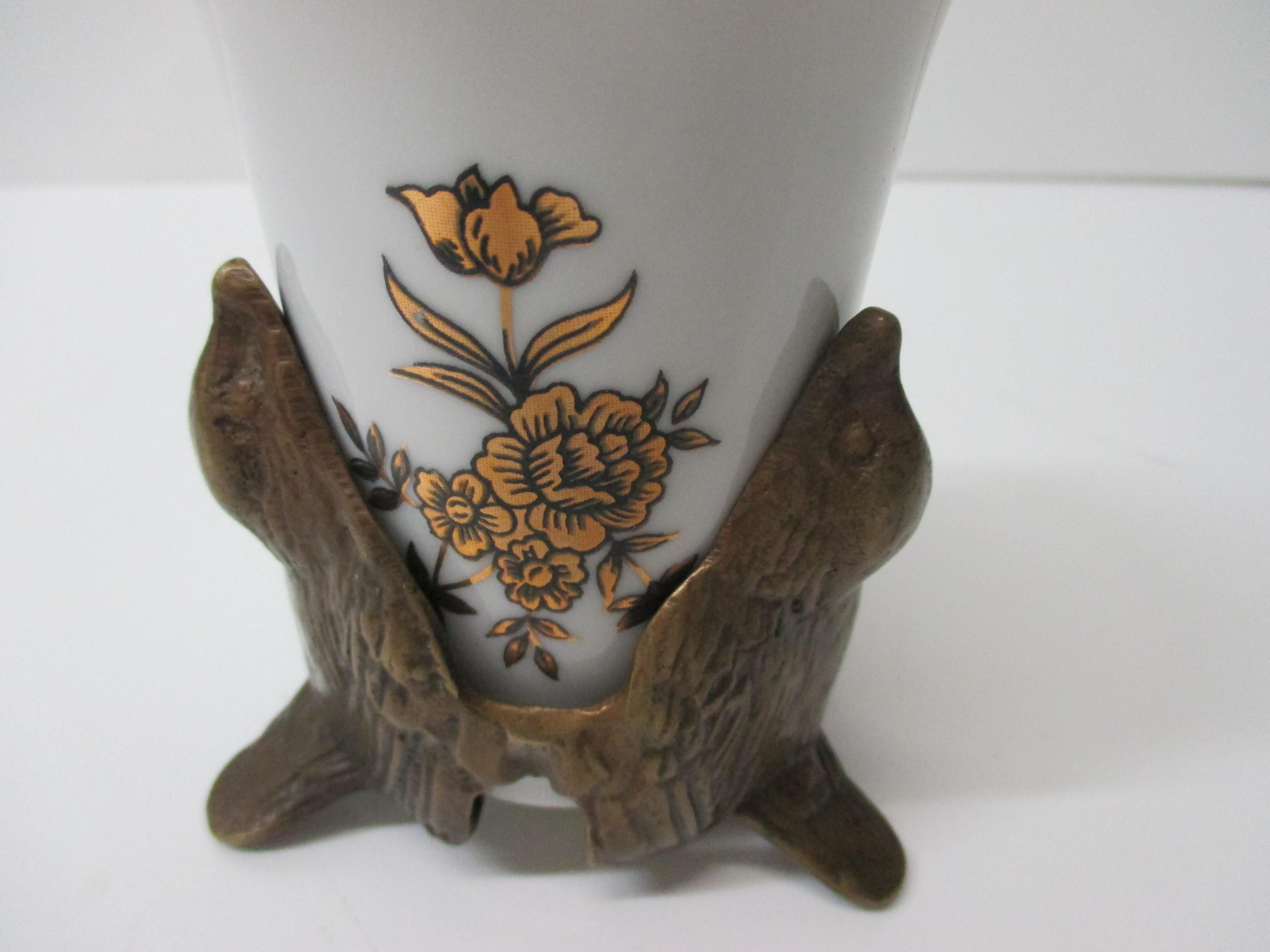 Vintage White and Gold Toothbrush Porcelain Cup With Brass Bird Stand.
With a brass birds base, holding the cup with a decorative motif of gold flowers in the front. 
Toothbrush holder or cup.
Size: 4 x 3.75 x 4