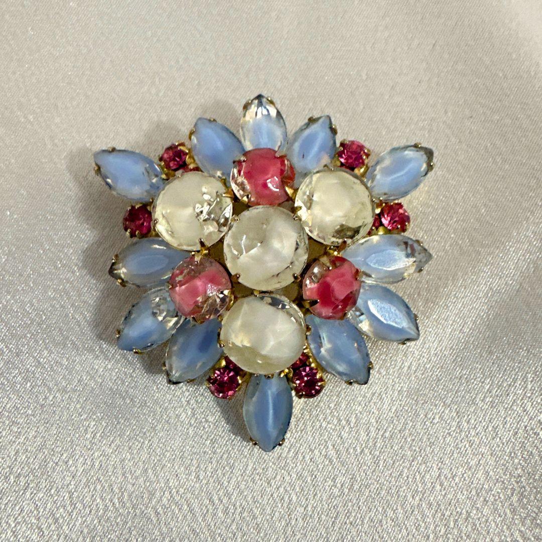 Dazzle and delight with this exquisite Vintage White Blue & Pink Glass and Rhinestone Brooch. A timeless piece that captures the essence of yesteryears, this brooch is a harmonious blend of delicate hues and intricate craftsmanship. The brooch