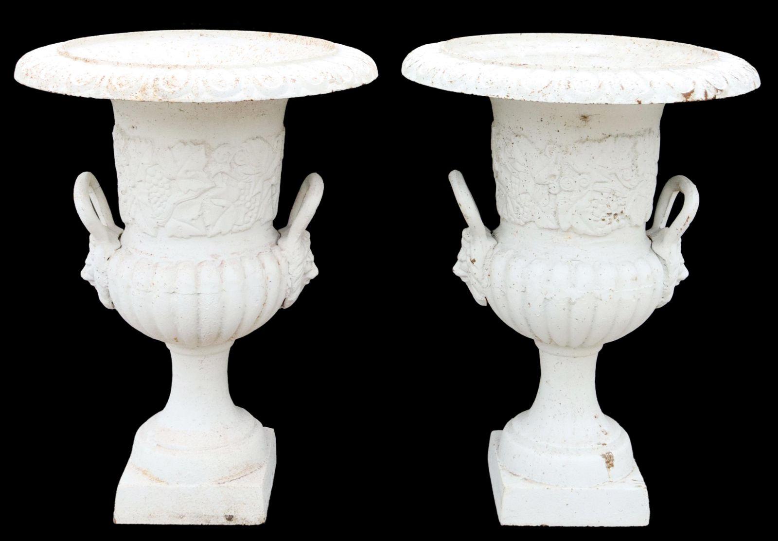 A pair of cast iron campana-form garden urn planters, in a white painted finish, having egg and dart rim, over grapevine and melon ribbed body, lion mask handles, rising on integral square base. No makers mark visible. Heavy and very sturdy. Perfect