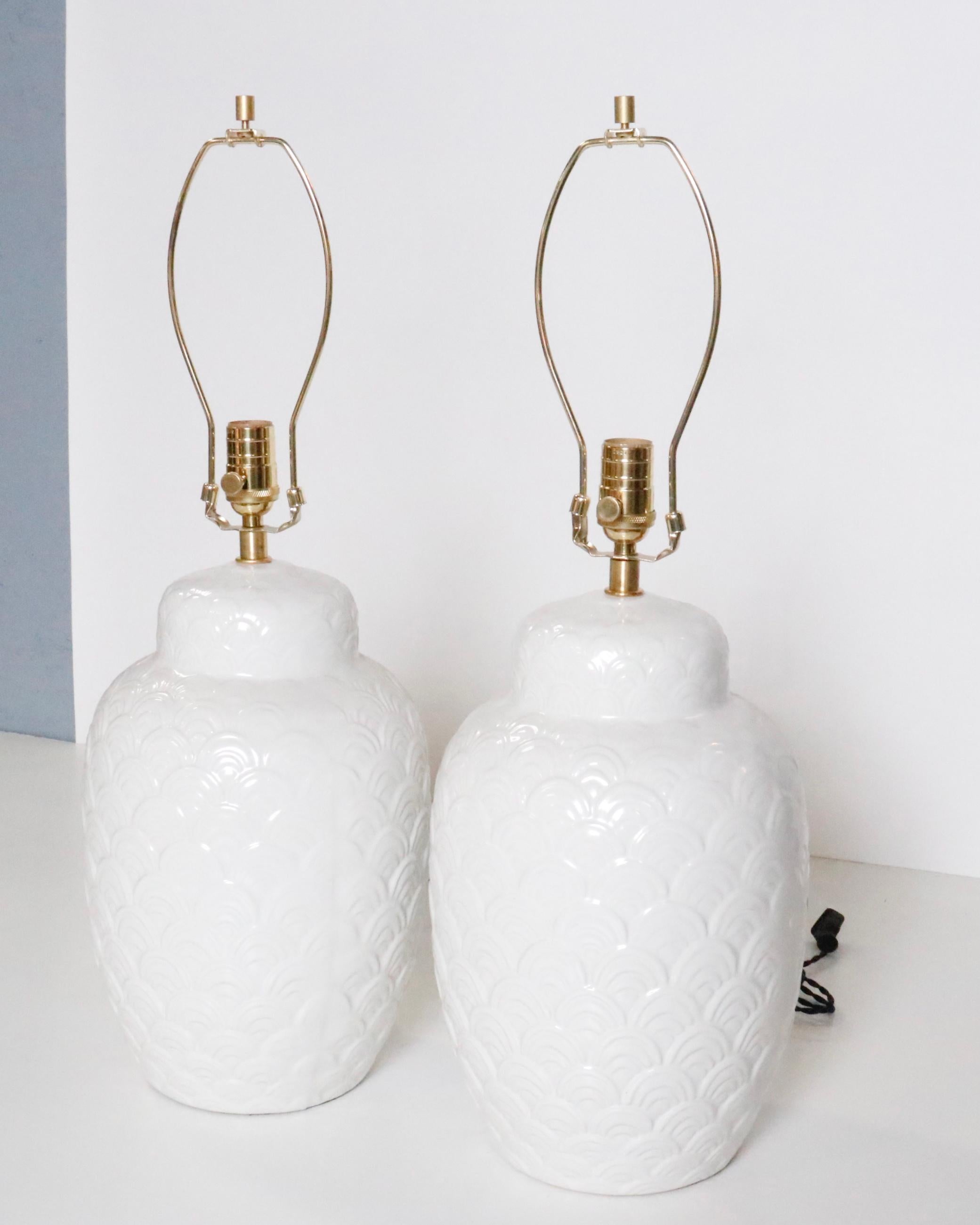 A pair of white ginger jar style ceramic table lamps.  USA. circa 1960.

Featuring a clasic shape; newly rewired with new sockets, brass hardware and French black silk twisted cord.

Shades not included.