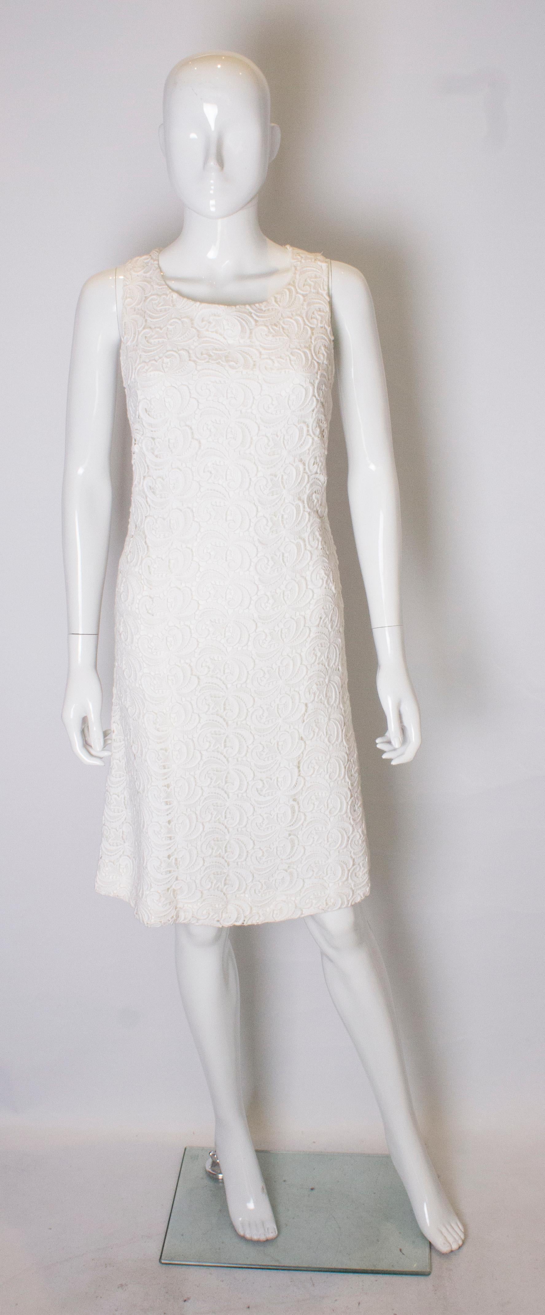 A head turning cocktail dress in white lace . The dress has a low round neckline, with crossover straps at the the back and a low back line. It is fully lined.