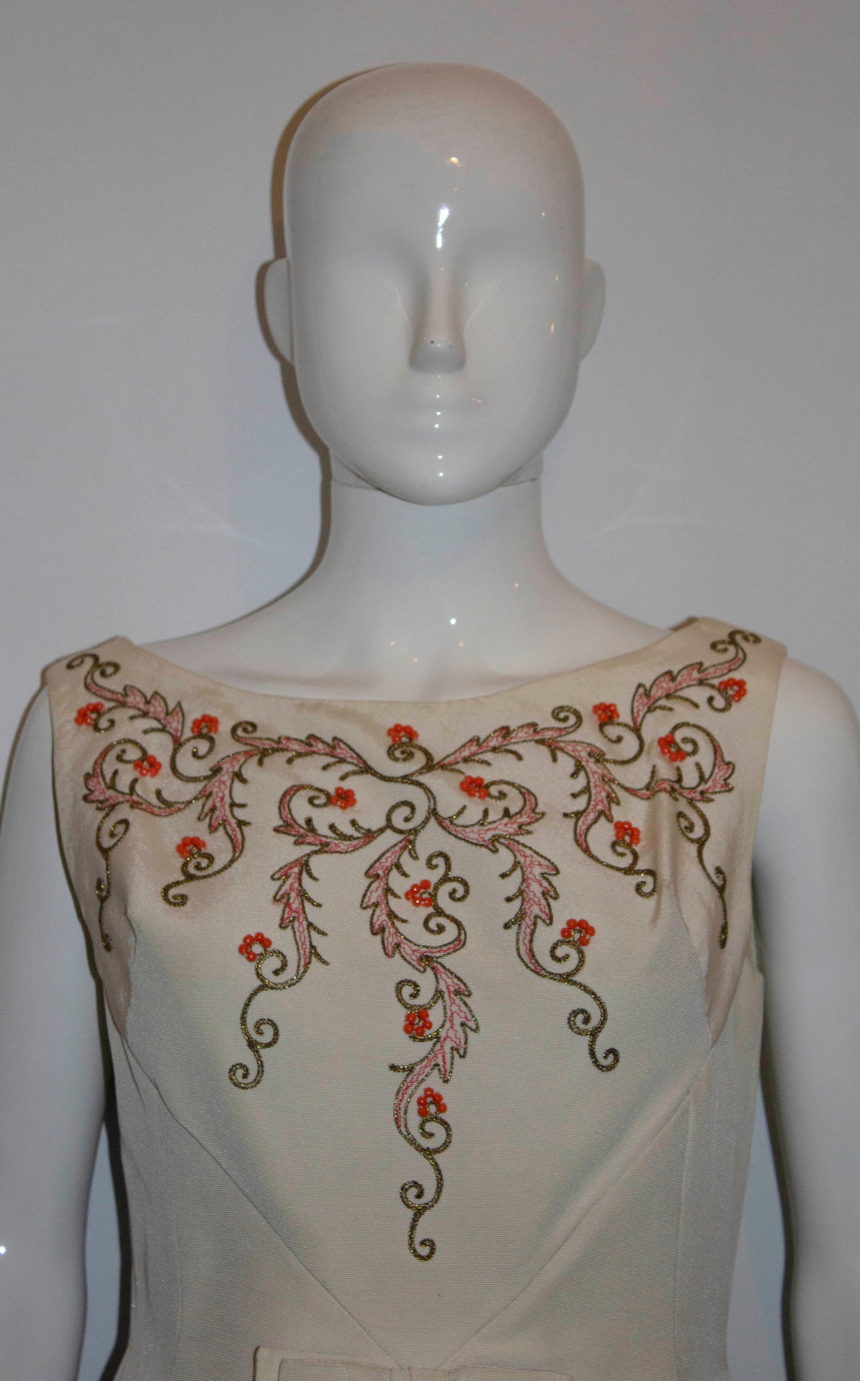 A lovely white vintage cocktail dress from the 1950's. The dress has a round neckline and has a pleat at the front with bow detail . It is decorated with coral colour beads and red and gold thread. 

Measurements: Bust 37'', waist 28'',length 41''